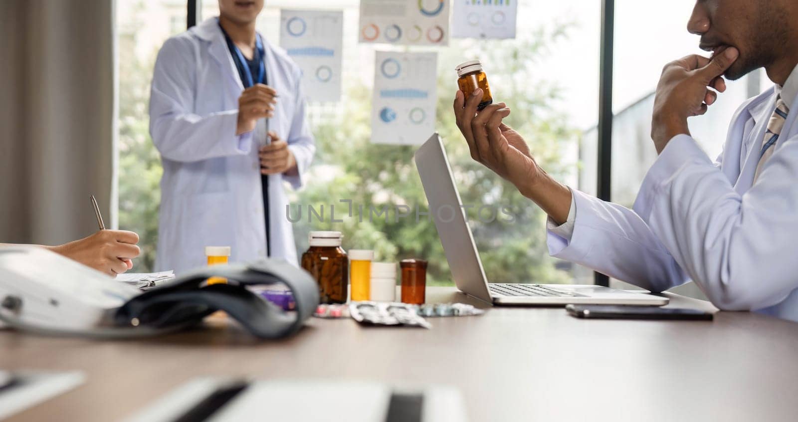 A doctor thoughtfully analyzing medication options during a meeting with colleagues, focusing on patient care and treatment strategies.