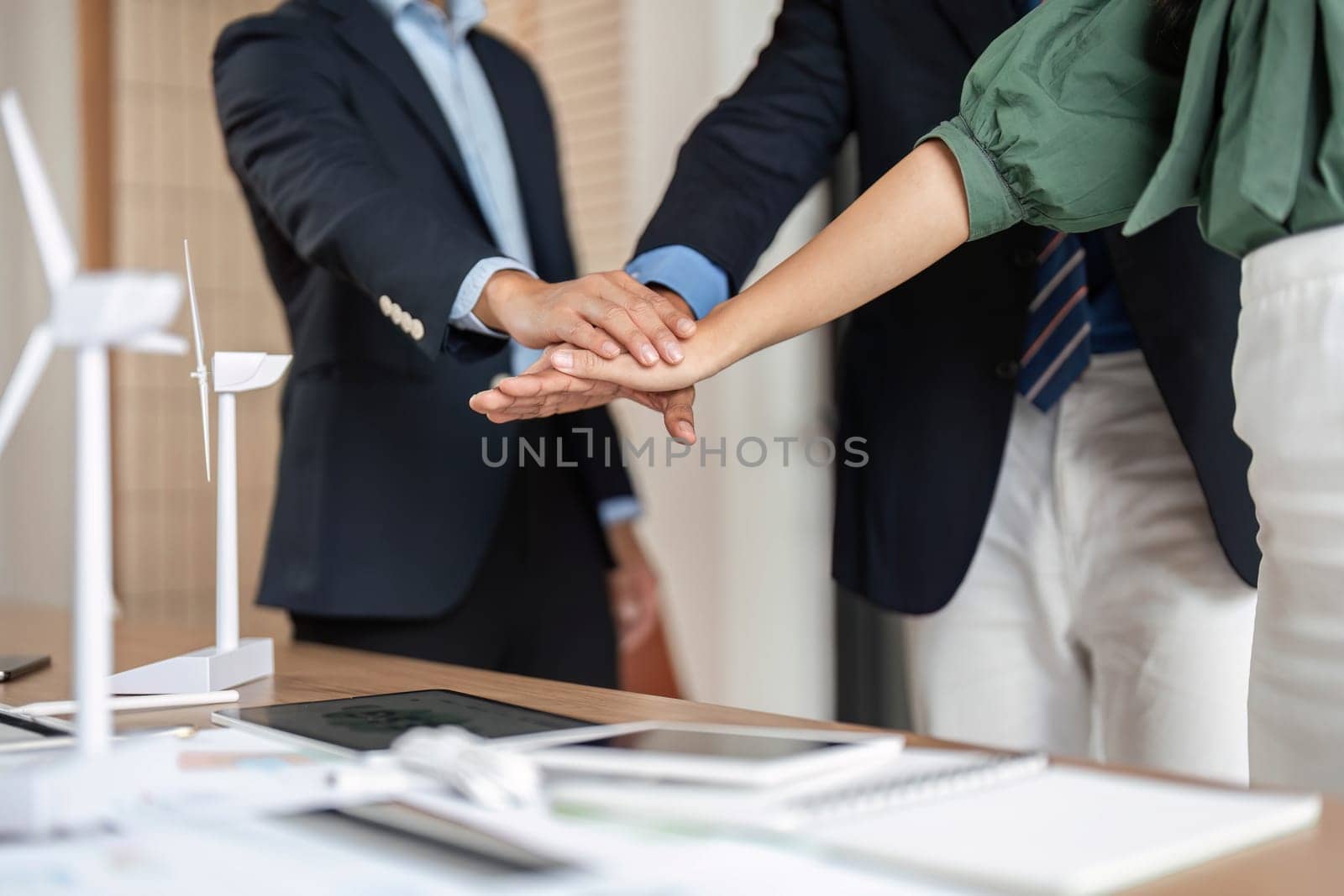A close-up of diverse hands coming together in a meeting, symbolizing teamwork, partnership, and commitment to sustainability in the professional setting.