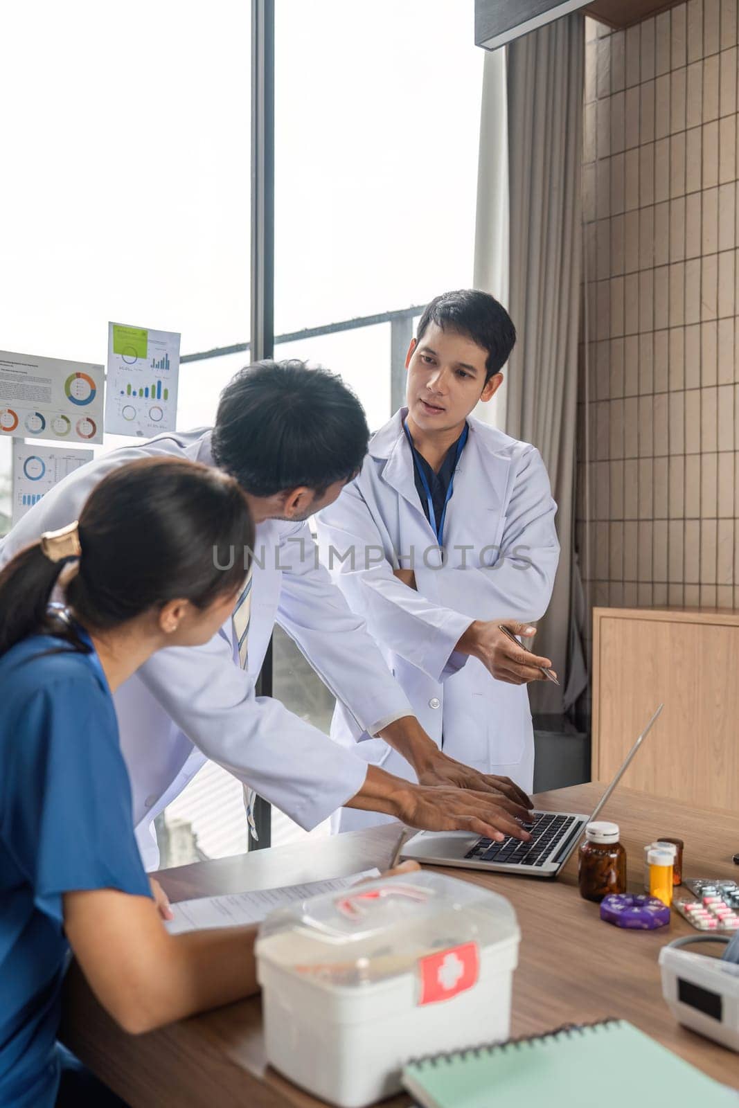 A doctor engaging with colleagues to discuss patient care strategies using a laptop and medical data during a meeting.