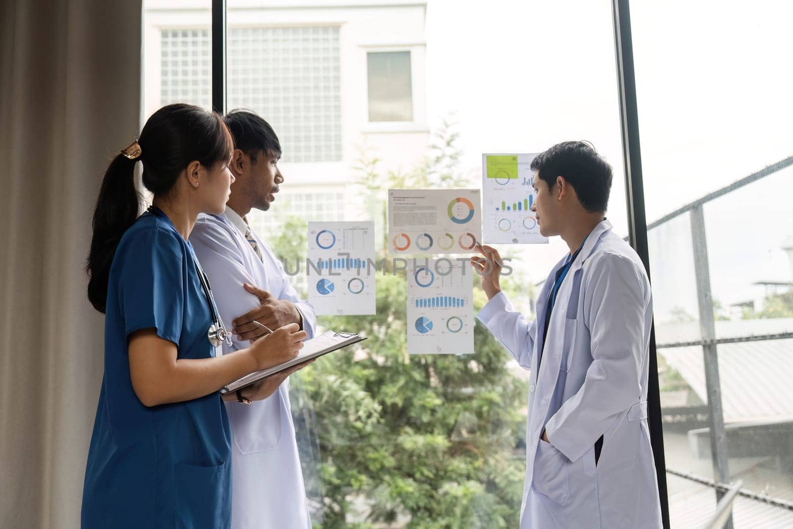 Three medical professionals working together to interpret health charts, emphasizing cooperation and data-driven patient care.
