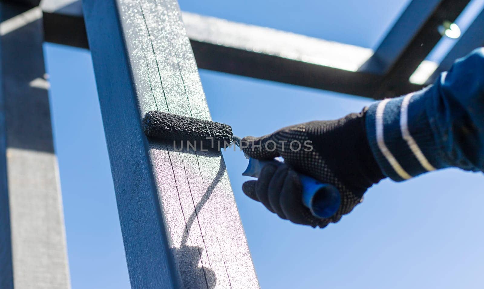 Man painting wooden poles. Selective focus. people.