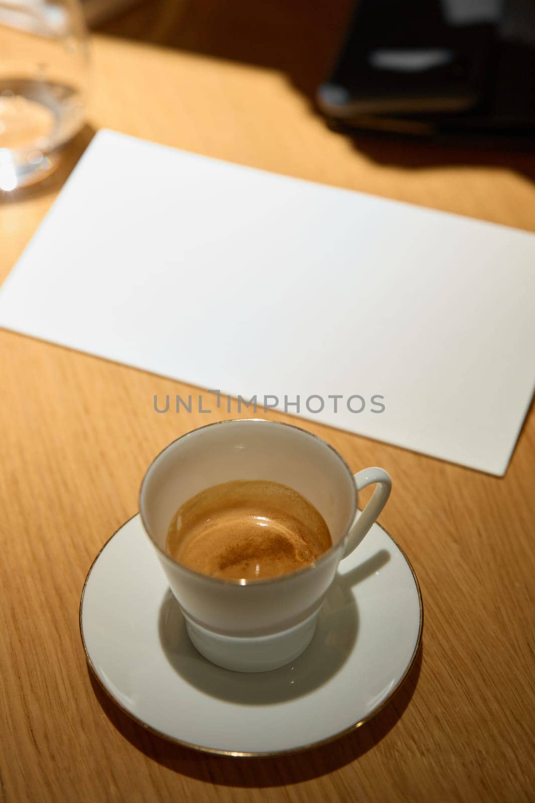 a cup of espresso coffee is on the table, next to it is a restaurant menu, a glass of water, an overhead light. High quality photo