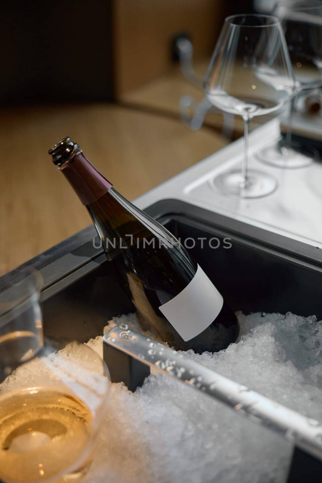 Bottle of champagne is cooled in a niche with ice in the restaurant, local lighting, wine cabinet, decanters for sparkling wine. High quality photo