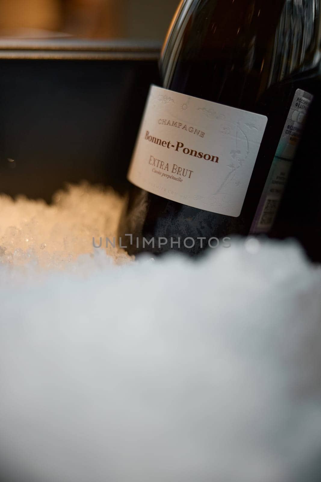 Russia, St.Petersburg, 29 April 2025: Bottle of champagne brand Bonnet-Ponson is cooled in a niche with ice in the restaurant, local lighting, wine cabinet, decanters for sparkling wine. High quality photo