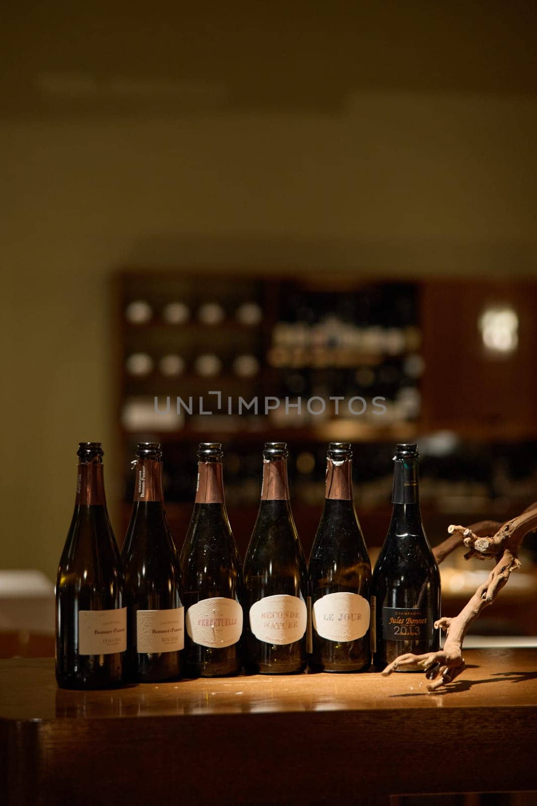 Russia, St.Petersburg, 29 April 2025: Several bottles of champagne brand Bonnet-Ponson are on the bedside table in the center of the restaurant, local lighting, wine cabinet, stylish table setting. High quality photo