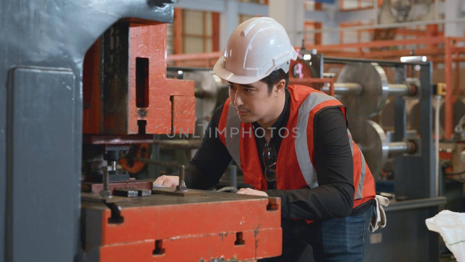 Engineer or operator wearing a safety suit working bending metal sheet by sheet press bending machine in workshop, Worker in factory at metal folding machine putting work piece at factory industry