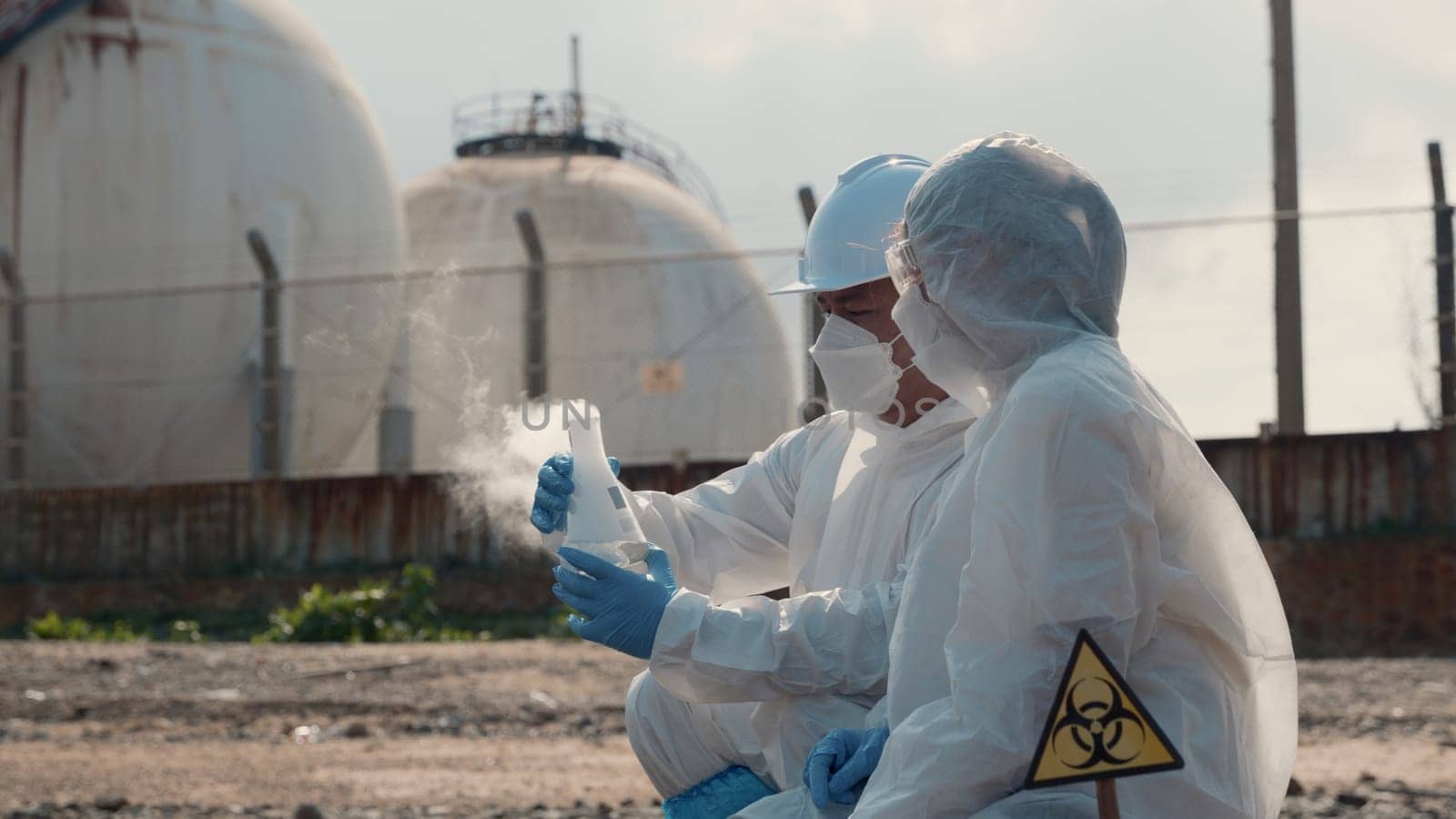Ecologist sampling water toxic chemicals from river with test tube glass and have white smoke, Biologist wear protective suit and mask collects sample waste water from industrial, problem environment