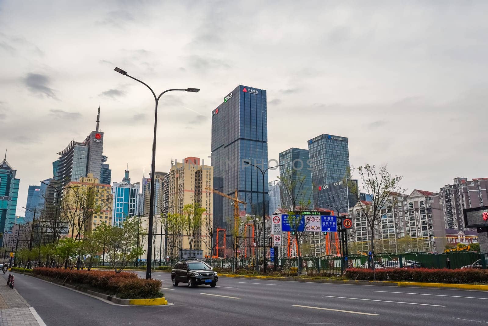 Shanghai, China - 1 April 2025: Modern skyscrapers and financial buildings in Pudong district with light traffic and city signs on a cloudy day