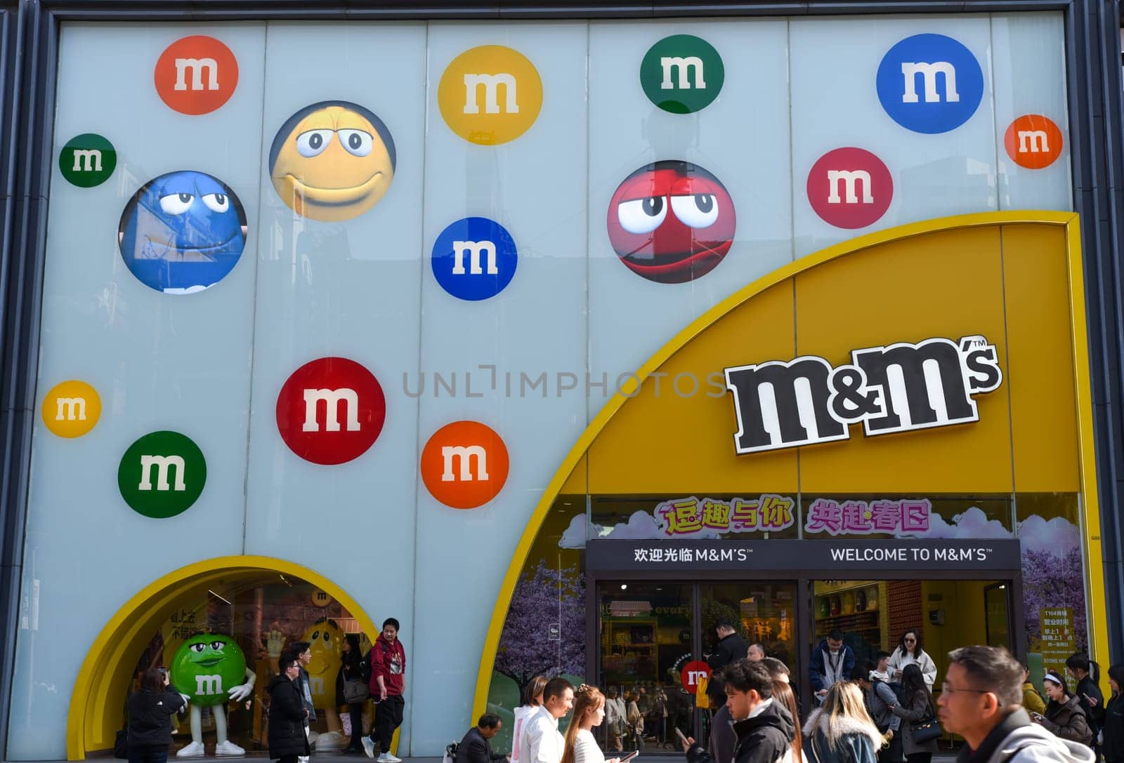 Shanghai, China - 1 April 2025: Crowds of tourists gather outside the official M&M's World store on Nanjing Road Pedestrian Street, Shanghai's famous shopping district. The store's vibrant signage and colorful facade dominate the scene.