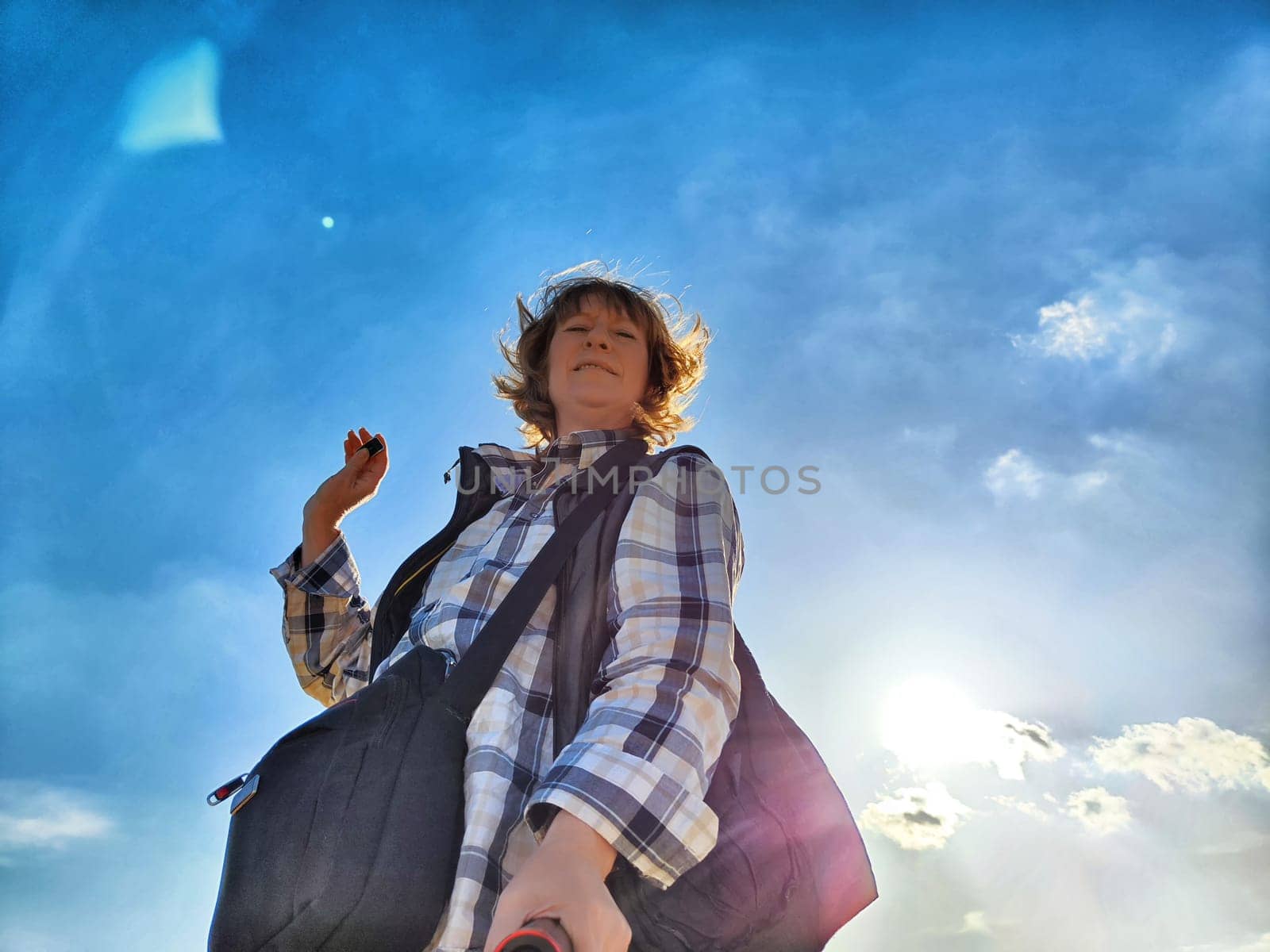 Blonde woman captures a selfie while exploring outdoors, enjoying her travel adventure under a sunny sky.