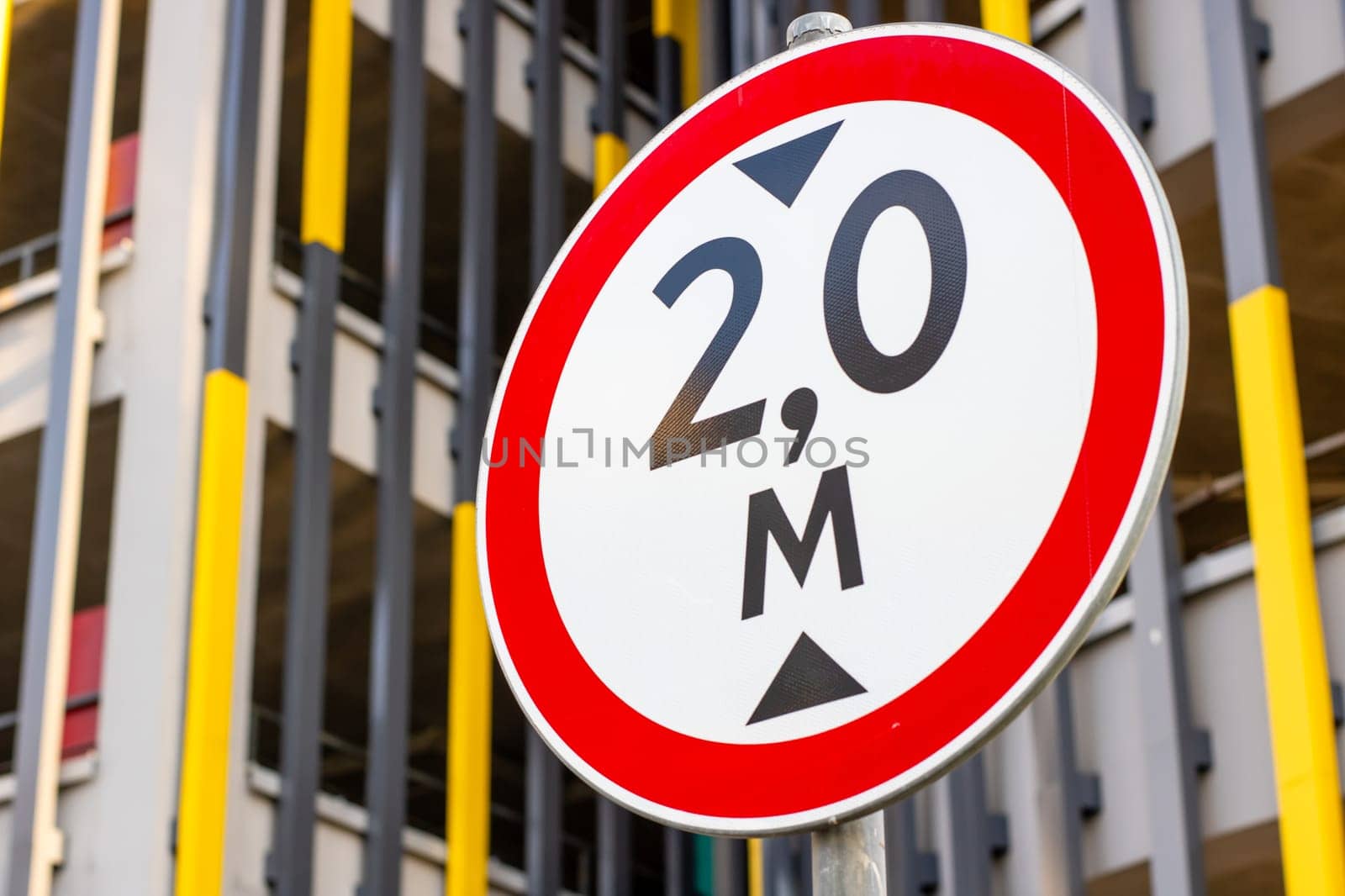 A clear red and white sign prominently displays the height restriction of 2.0 meters for vehicles passing under it, ensuring compliance
