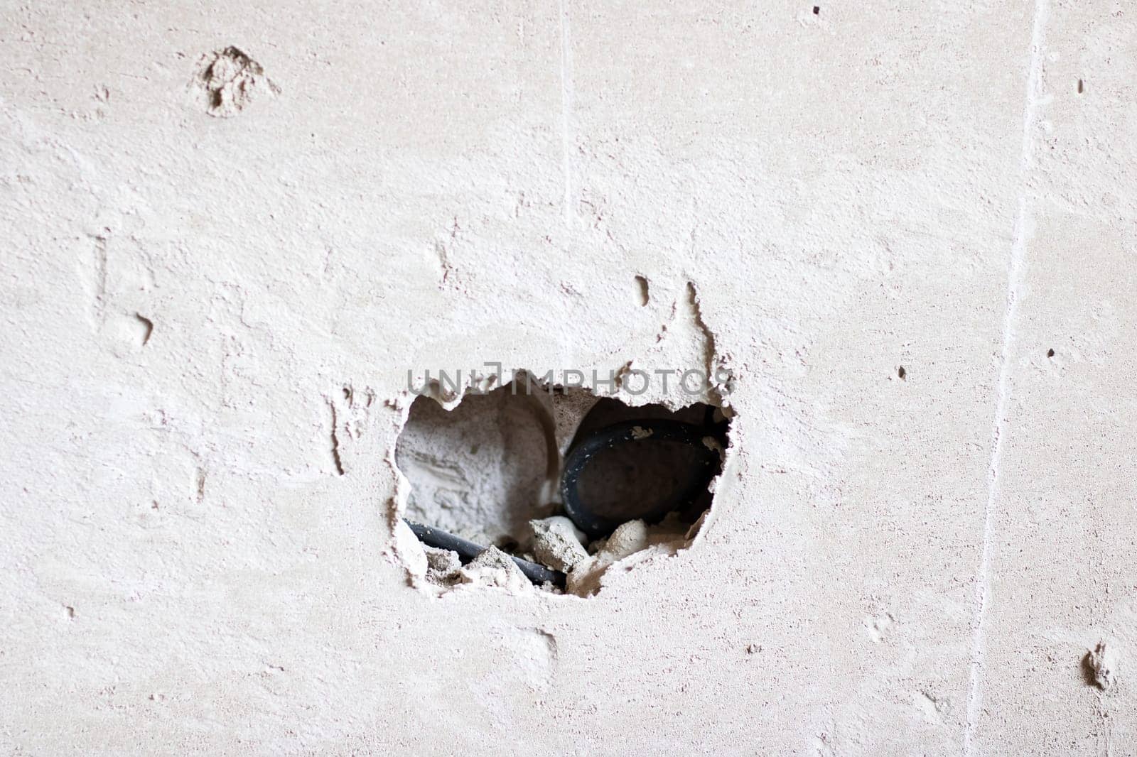 There exists a hole in a concrete wall, and scattered footprints can be seen around it, indicating some movement or activity nearby