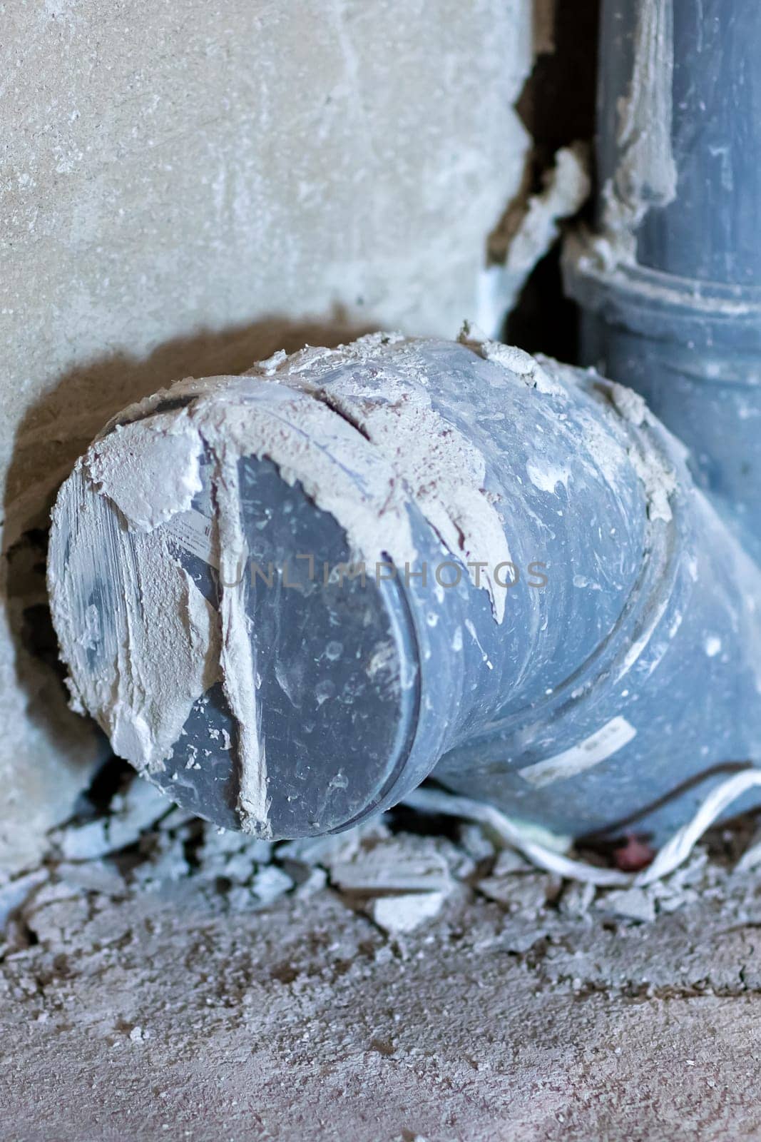 A broken pipe now lies on the ground adjacent to an old concrete wall, creating an interesting scene for still life photography enthusiasts