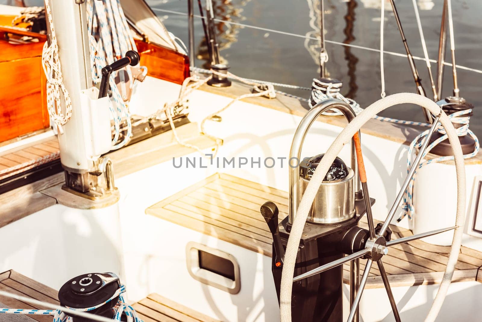 Sailing boat deck with steering wheel and nautical equipment in sunlight, 