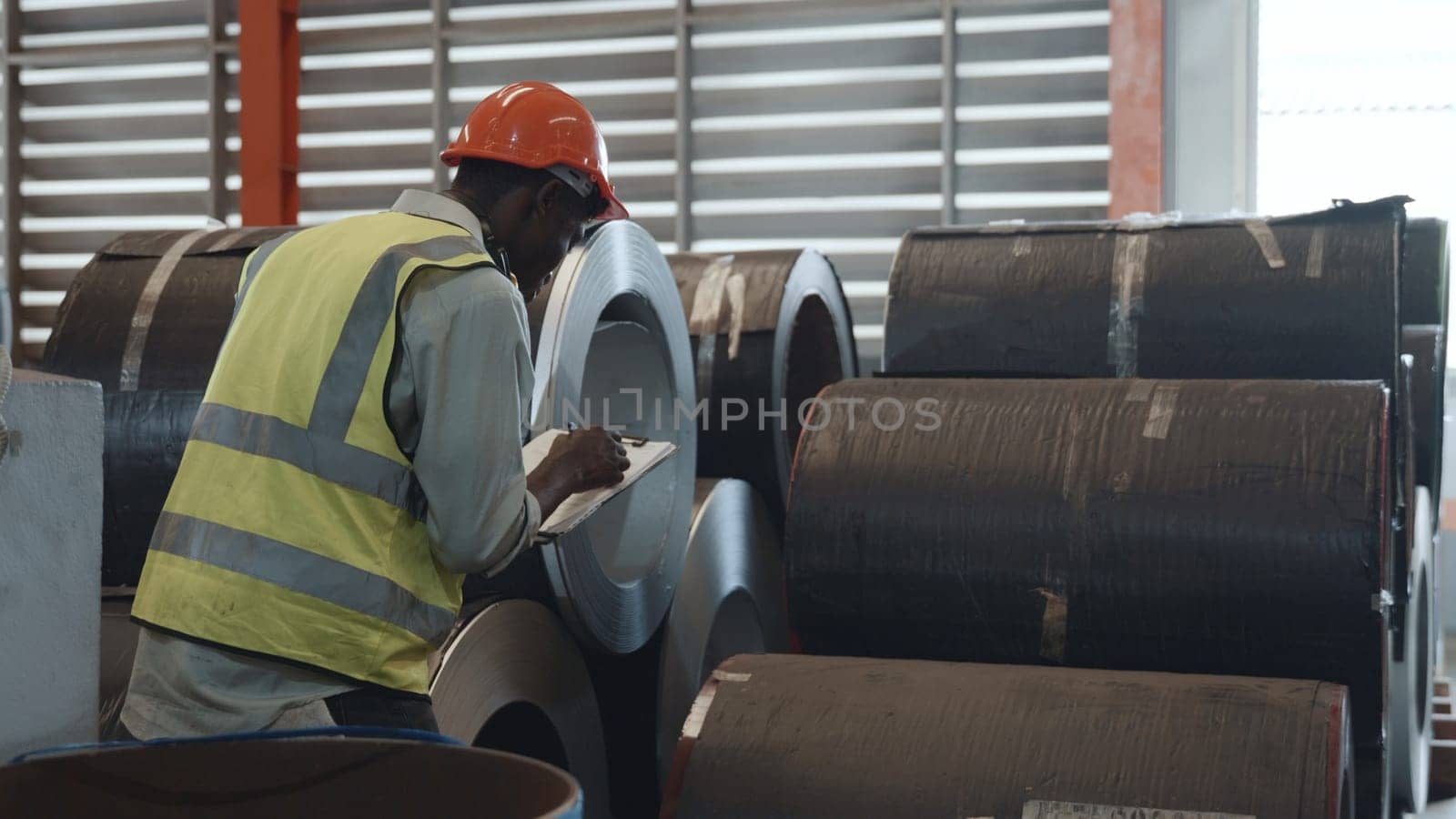 Two black workers engineer factory textile inspection and checking inventory levels of goods of roll metal sheet roof in warehouse they talking together and do work with products ready for shipment