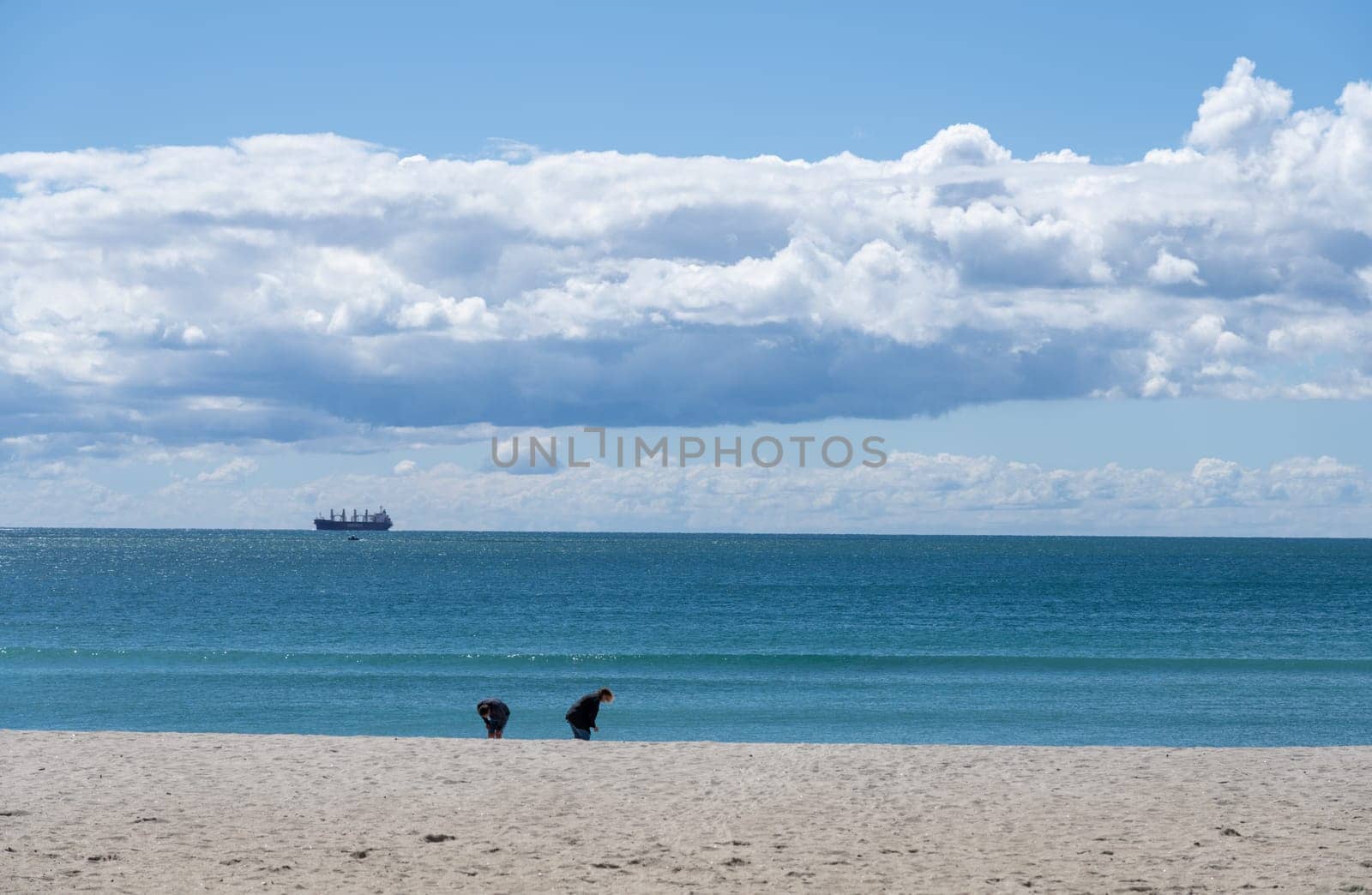 Tauranga New Zealand - March 22 2023: Mount Maunganui Main Beach background scene with cargo ship on distant horizon