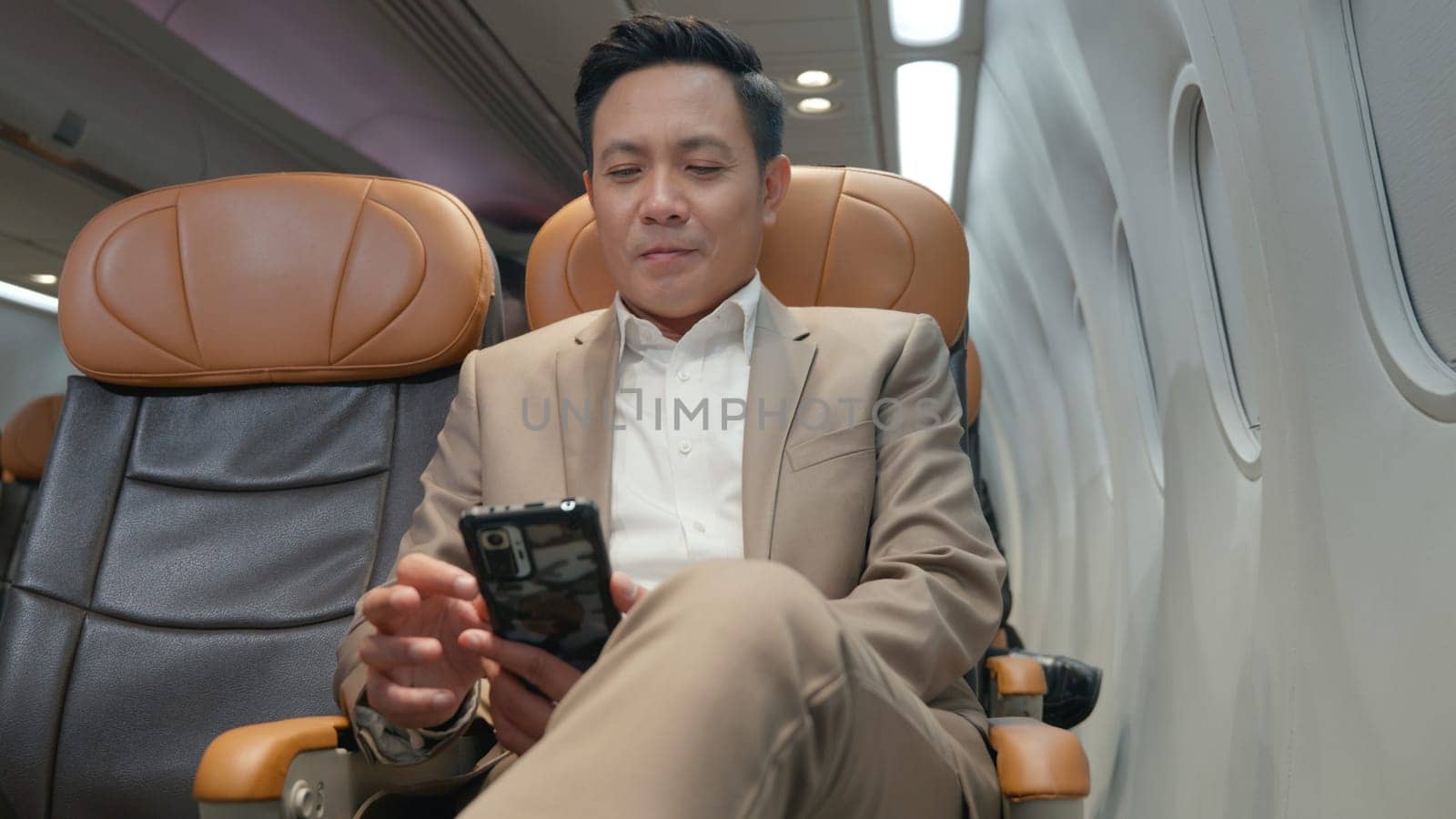 Passenger businessman using mobile phone test wifi connection in plane during flight, Asian man typing smartphone read social and news during business trip travelling