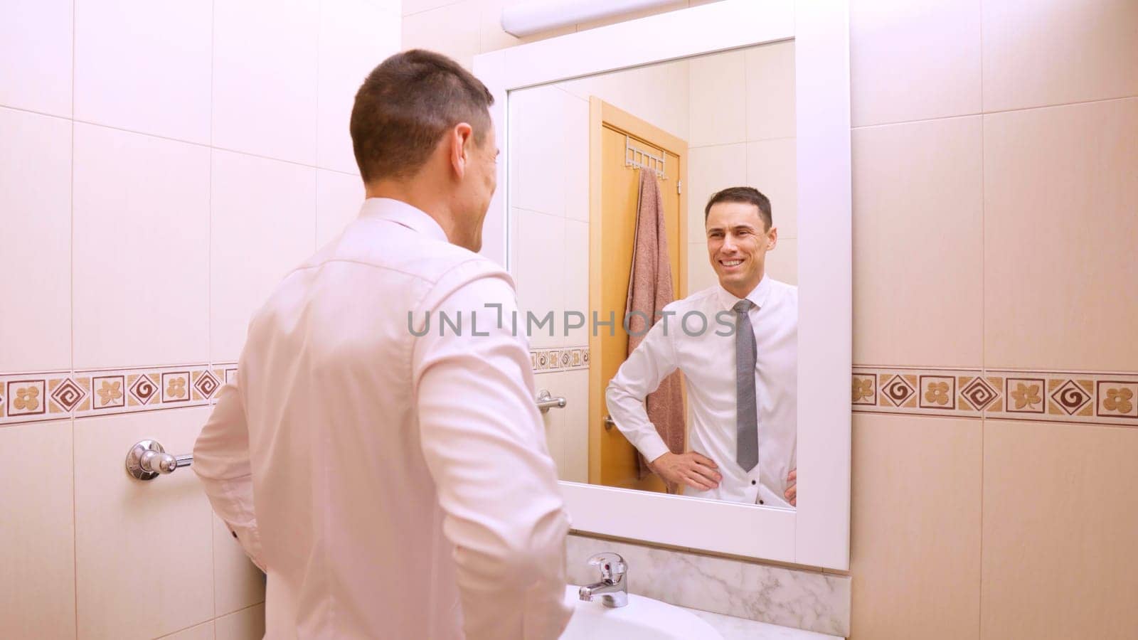 Businessman getting ready for work, smiling at his reflection in the bathroom mirror, feeling confident and successful