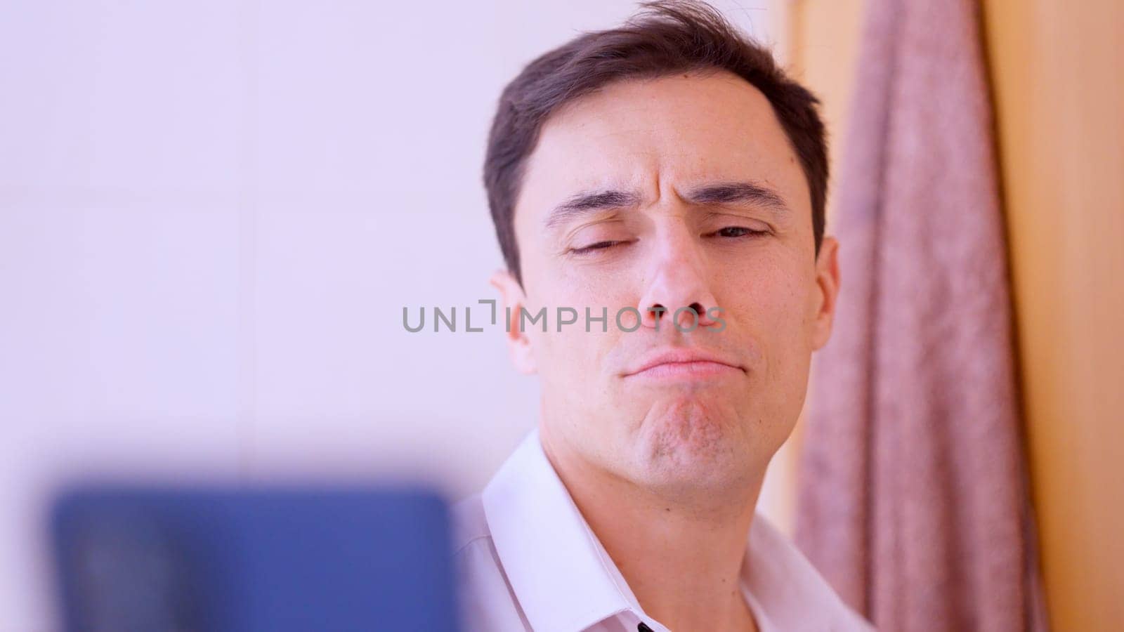 Businessman making a funny face while taking a selfie with his smartphone in a bathroom mirror
