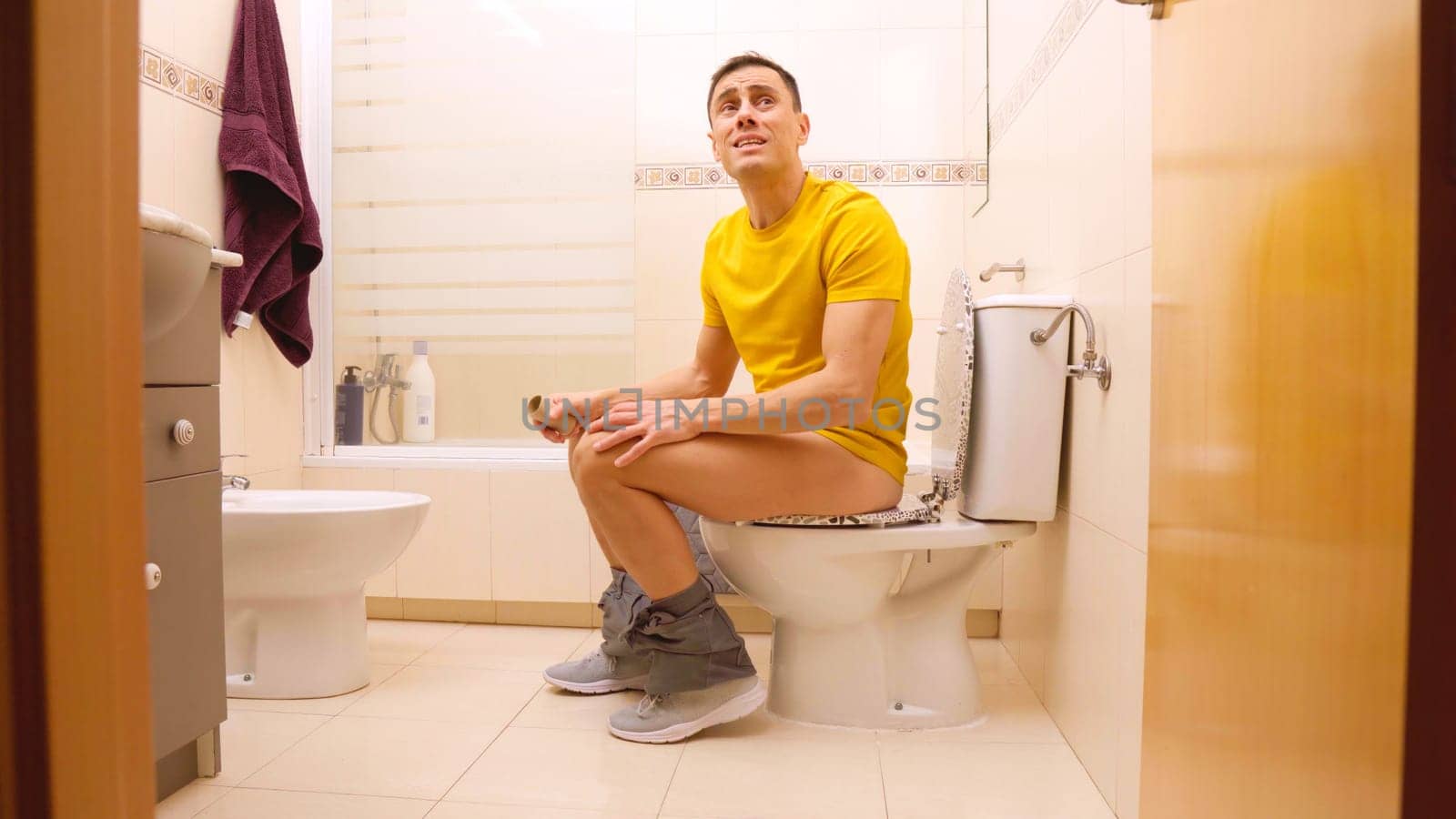 Man realizing he has finished toilet paper roll while sitting on toilet