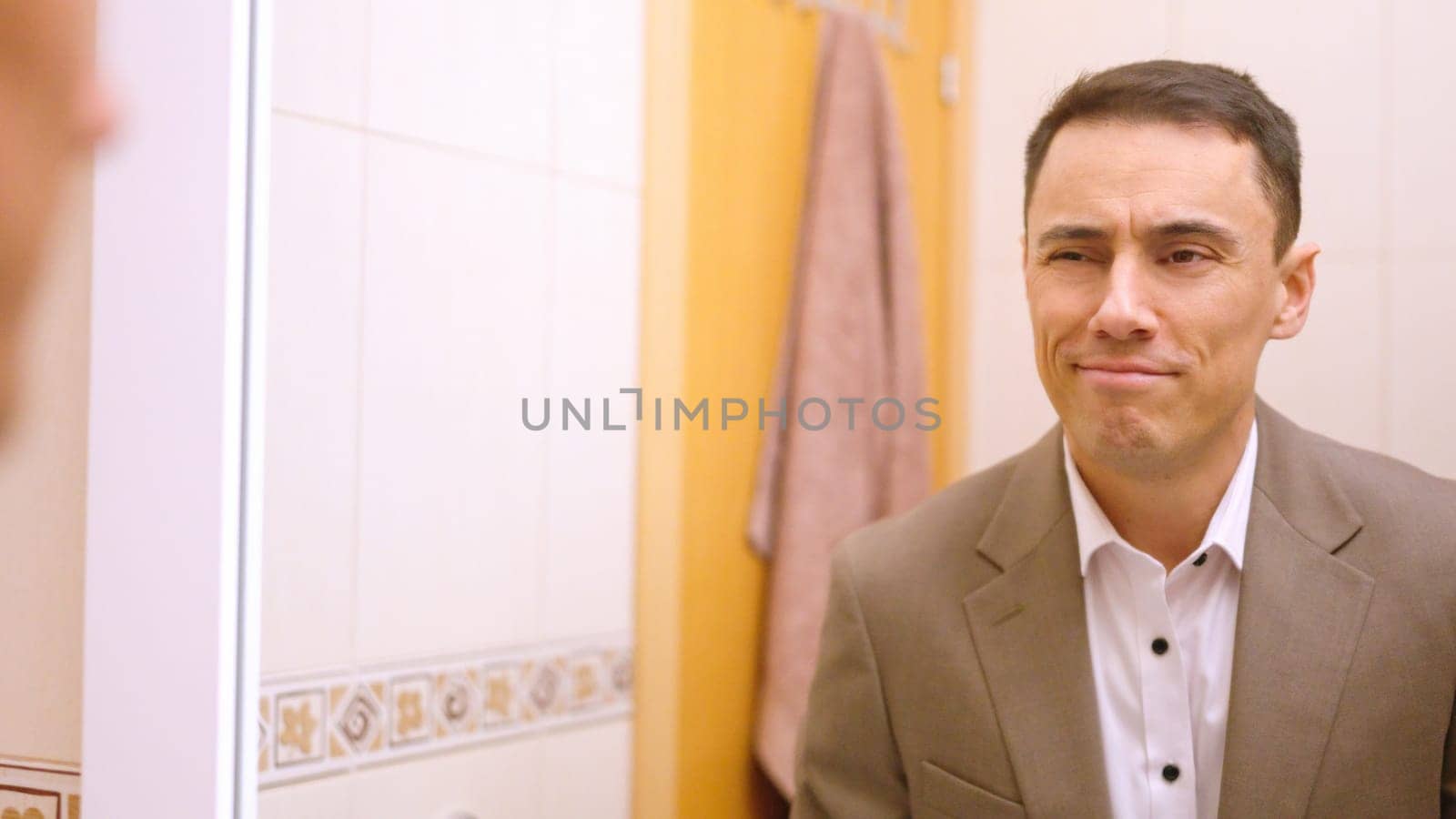 Businessman admiring himself in mirror, feeling confident and ready to start the workday