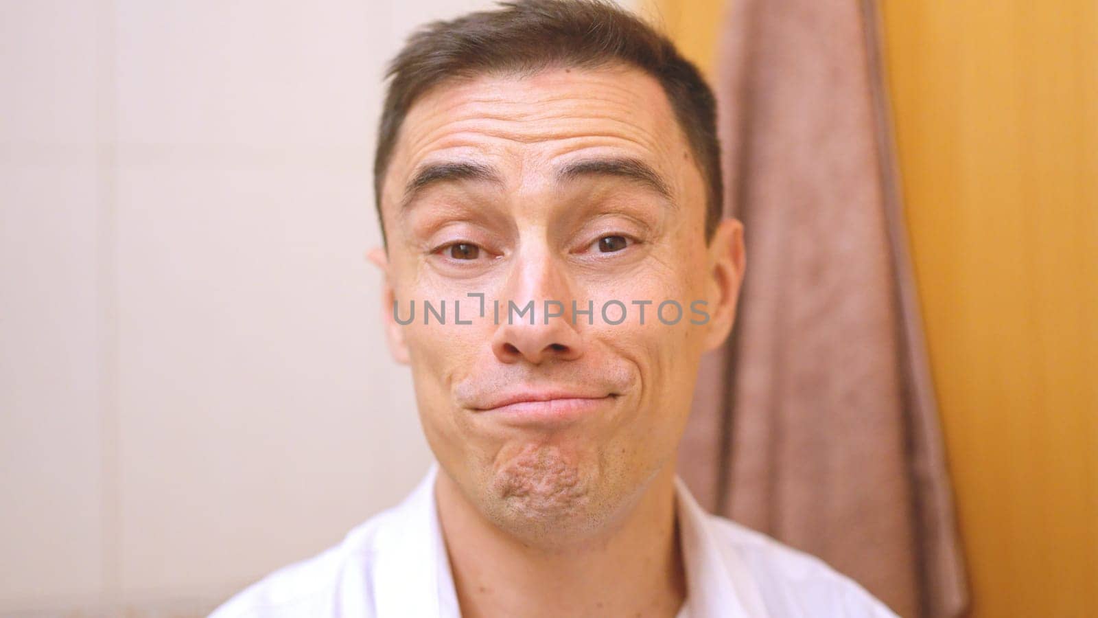 Close up of a friendly man making a funny, slightly embarrassed expression in a bathroom setting