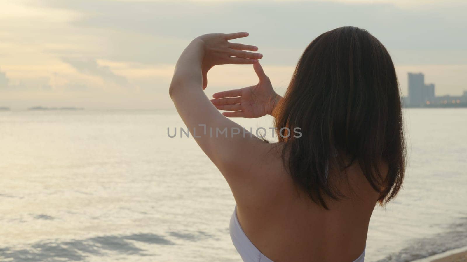 Back view, Beautiful woman wear bikini swimsuit making heart sign with hands at tropical beach, Happy Asian sexy female make shape with her fingers in holiday outside sunset, Summer travel vacation