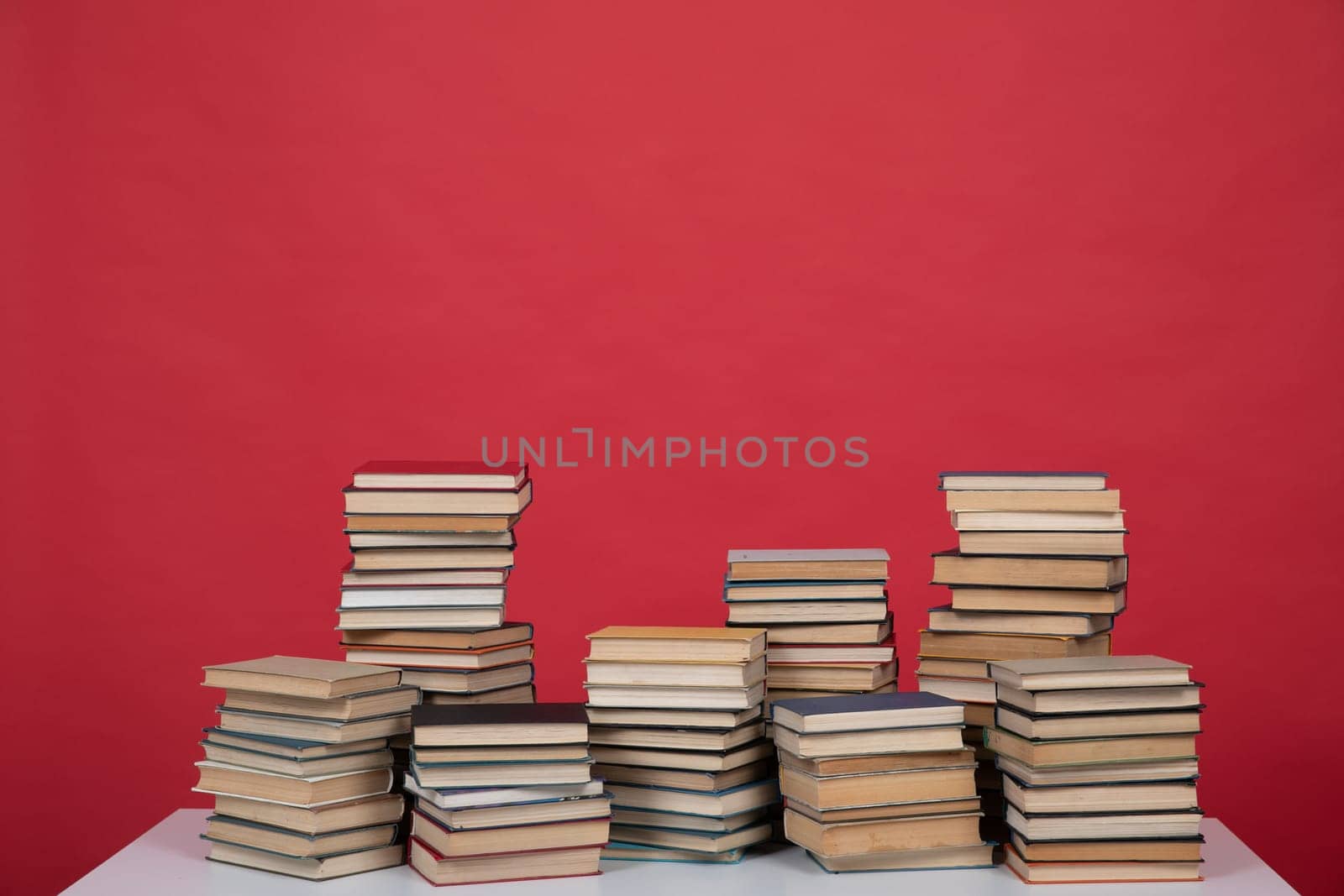 Stacks of educational books on the red background of the university library
