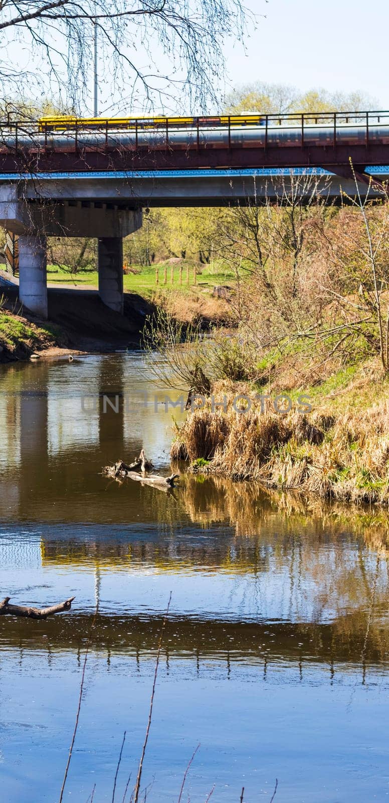 Yellow bus crossing the bridge, casting reflection in the water