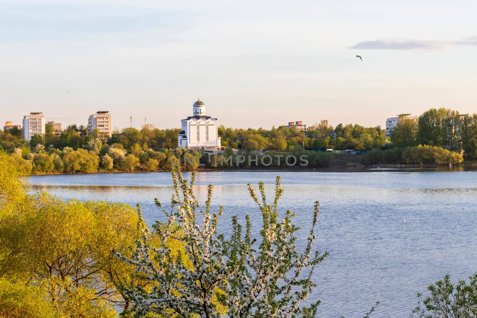 Sun is setting by the lake with city buildings and church on the background