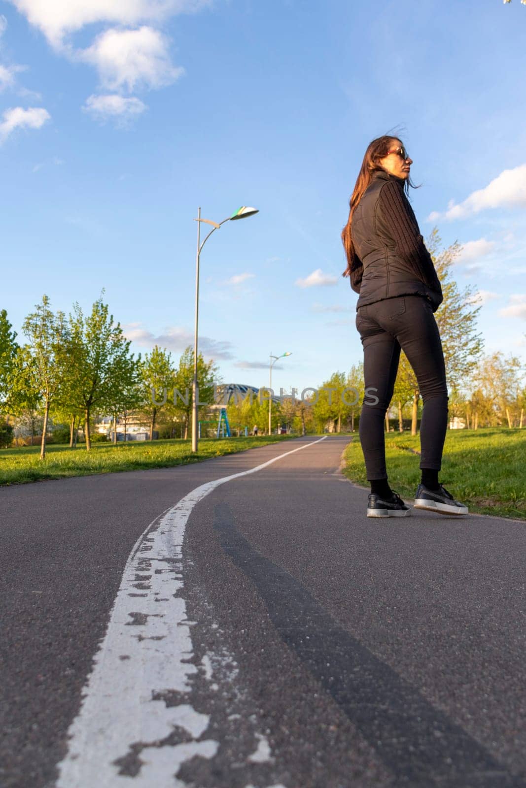 Asphalt surface of the jogging trail with painted dividing lane. Woman walking