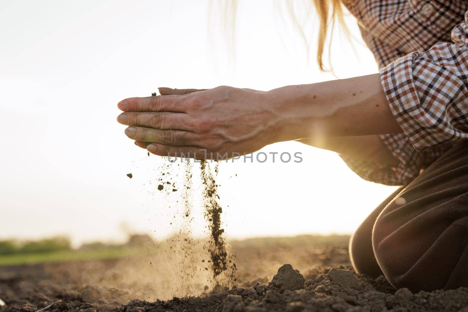 Farmer’s hands analyzing soil quality at sunset, symbolizing sustainable agriculture and land management.