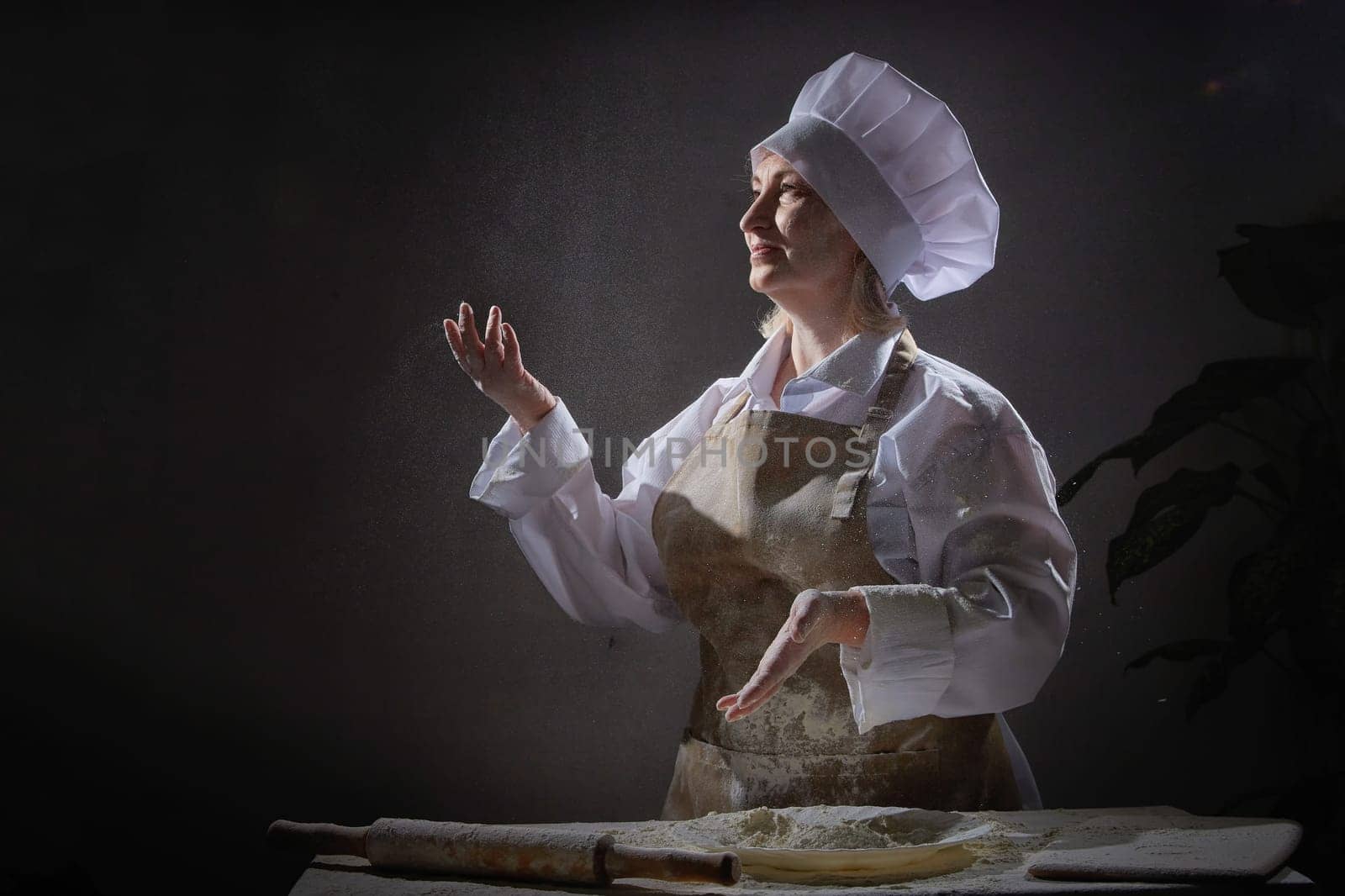 An elderly female cook joyfully plays with flour, creating a fun atmosphere during her cooking session in a unique kitchen.