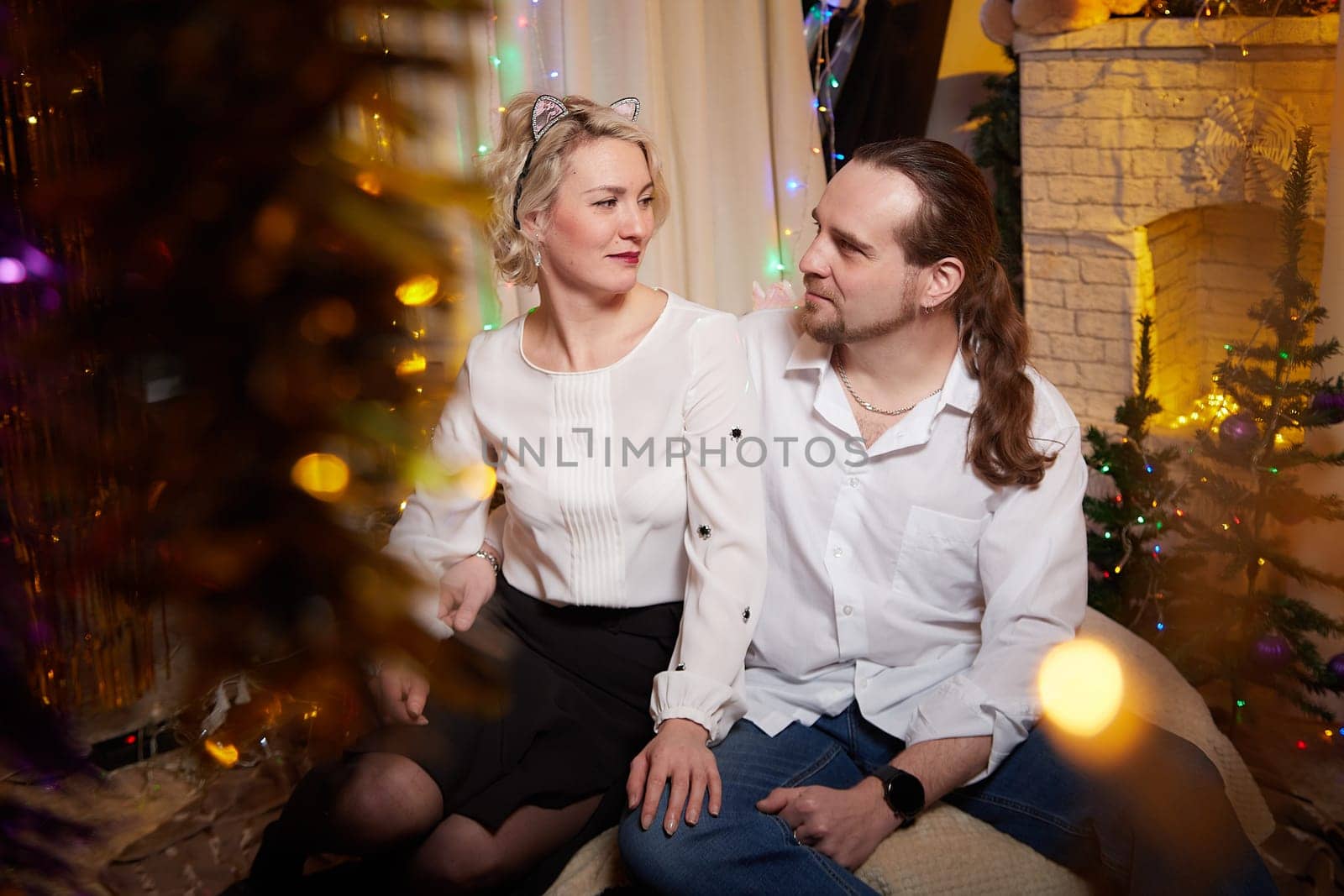 A couple celebrates Christmas and the New Year surrounded by festive decorations in their cozy home.