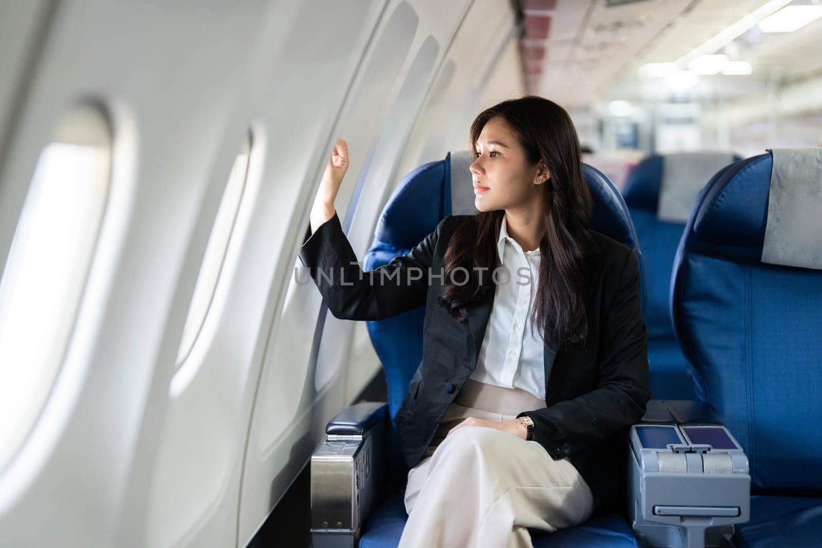 A businesswoman gazing thoughtfully out the airplane window, reflecting on her travel experience while enjoying the view.