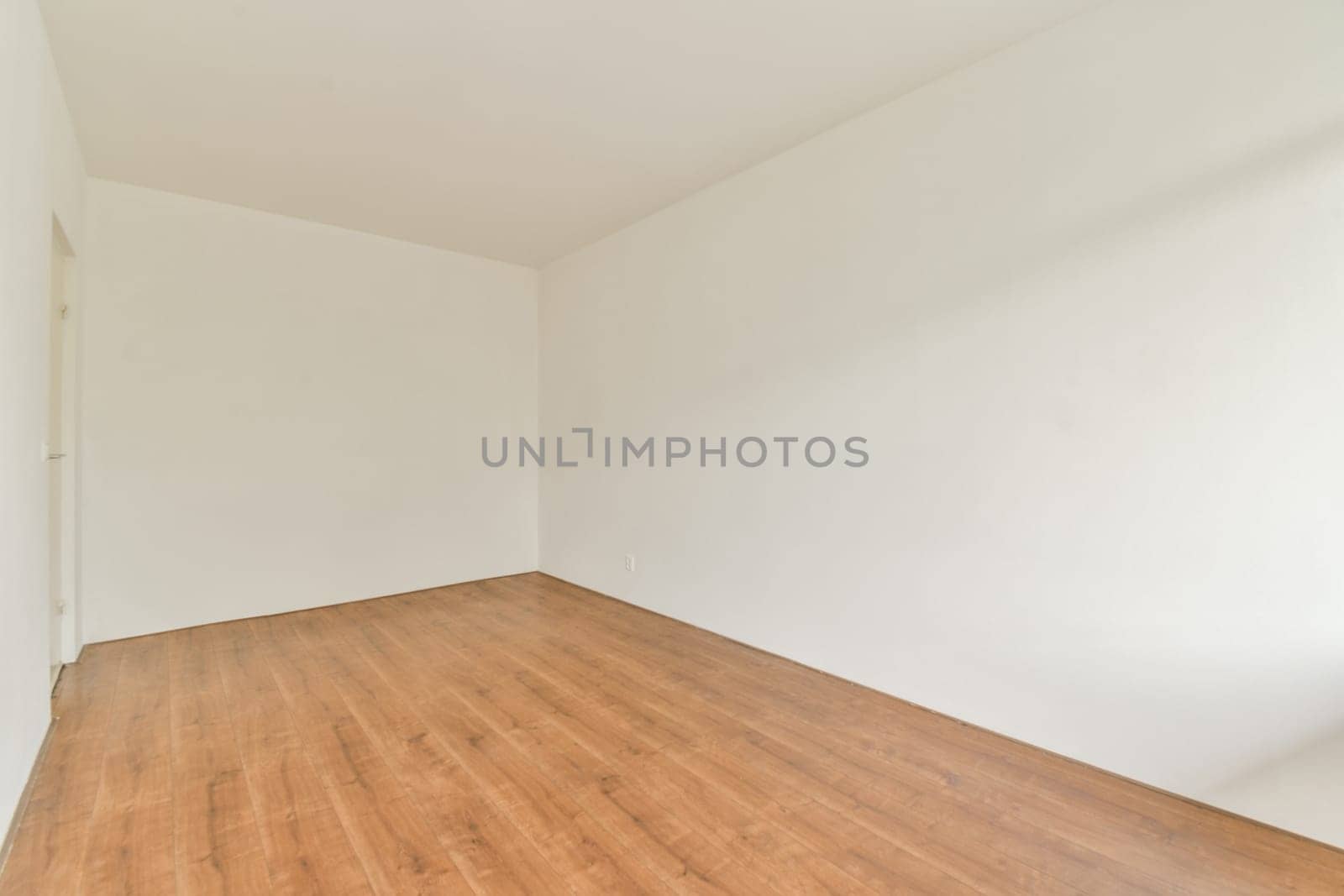 An empty room featuring a simple design with white walls and a wooden floor, providing a clean and spacious atmosphere for various uses.