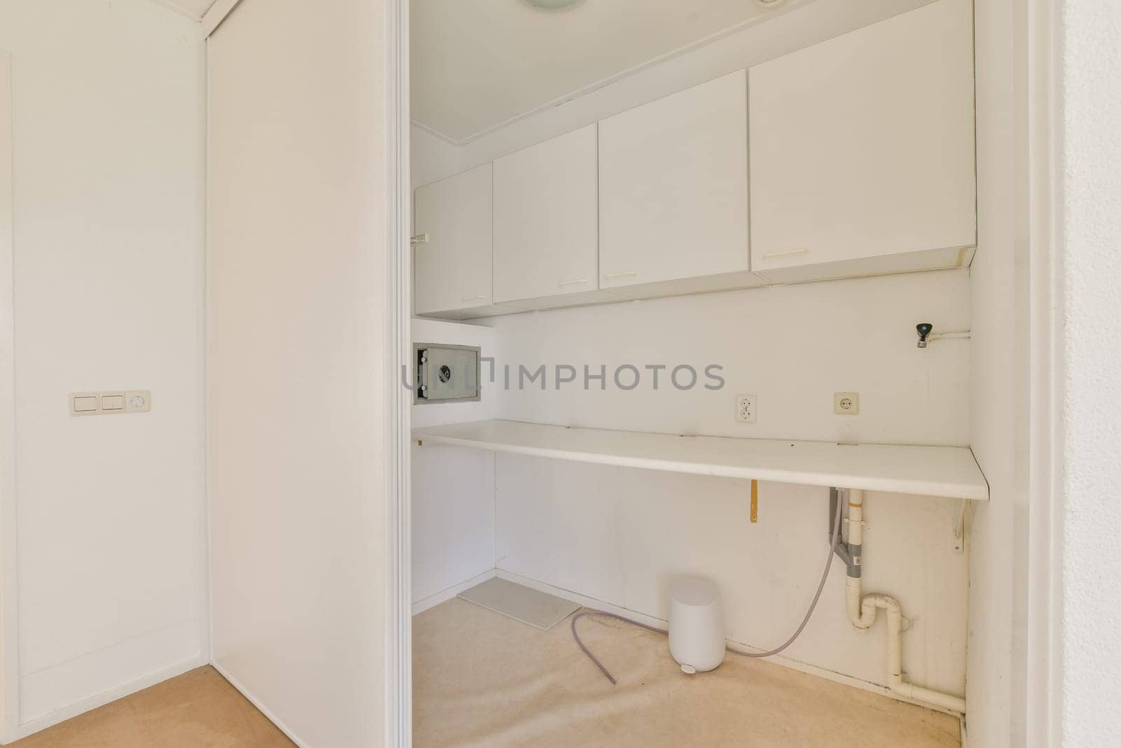 A clean and minimalist laundry room featuring white cabinetry and a simple layout. The design emphasizes functionality and simplicity, ideal for modern living.