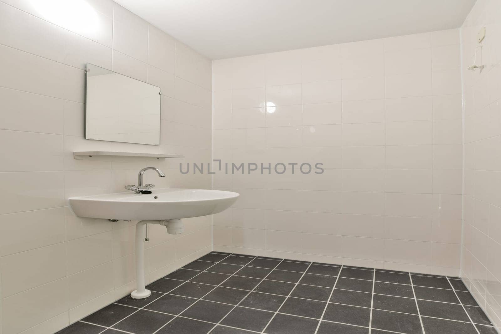 A clean and minimalist bathroom featuring a wall-mounted sink, a square mirror, and tiled flooring, creating a spacious and modern aesthetic.