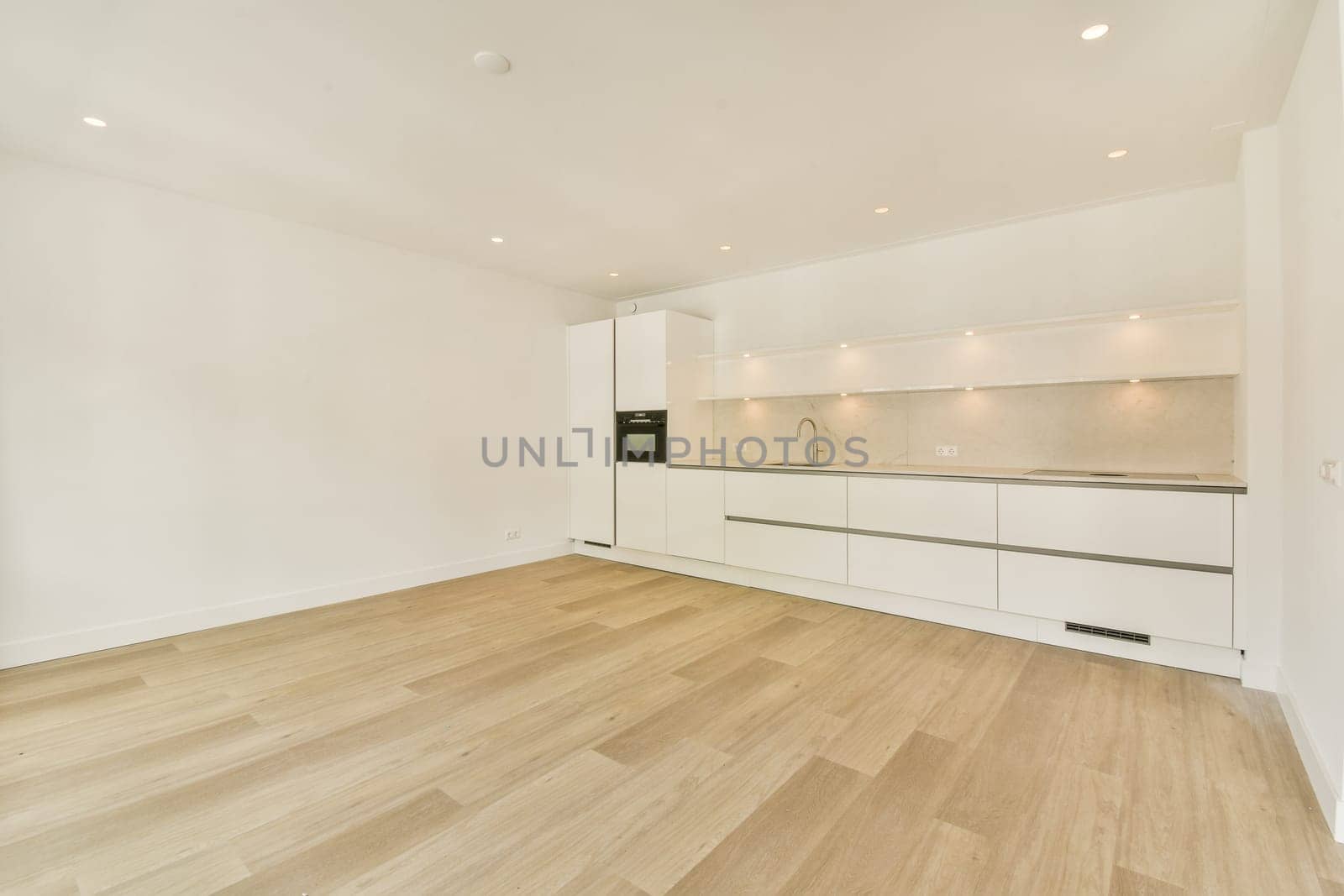 A clean and spacious modern kitchen featuring sleek white cabinetry and warm wooden flooring. Ideal for contemporary living spaces.
