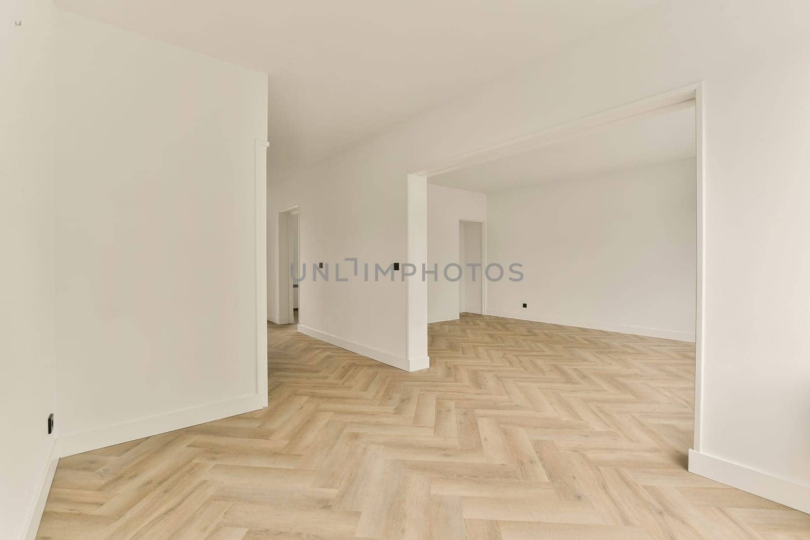 Spacious modern interior featuring light-colored walls and stylish herringbone patterned flooring, creating a contemporary and inviting atmosphere.