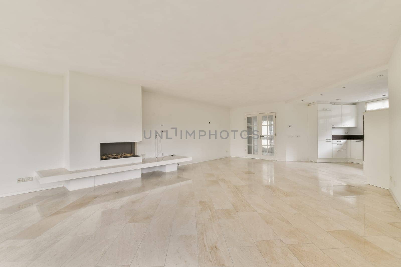 A bright and spacious living room features a sleek design with white walls, smooth flooring, and a modern fireplace, creating a tranquil atmosphere for relaxation.