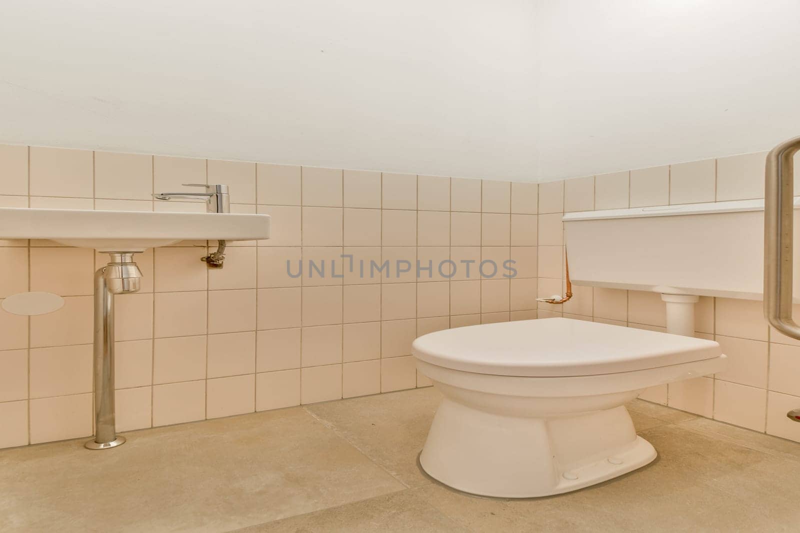 A clean and minimalistic design featuring beige tiles and simple fixtures, highlighting a toilet and sink in a spacious layout.