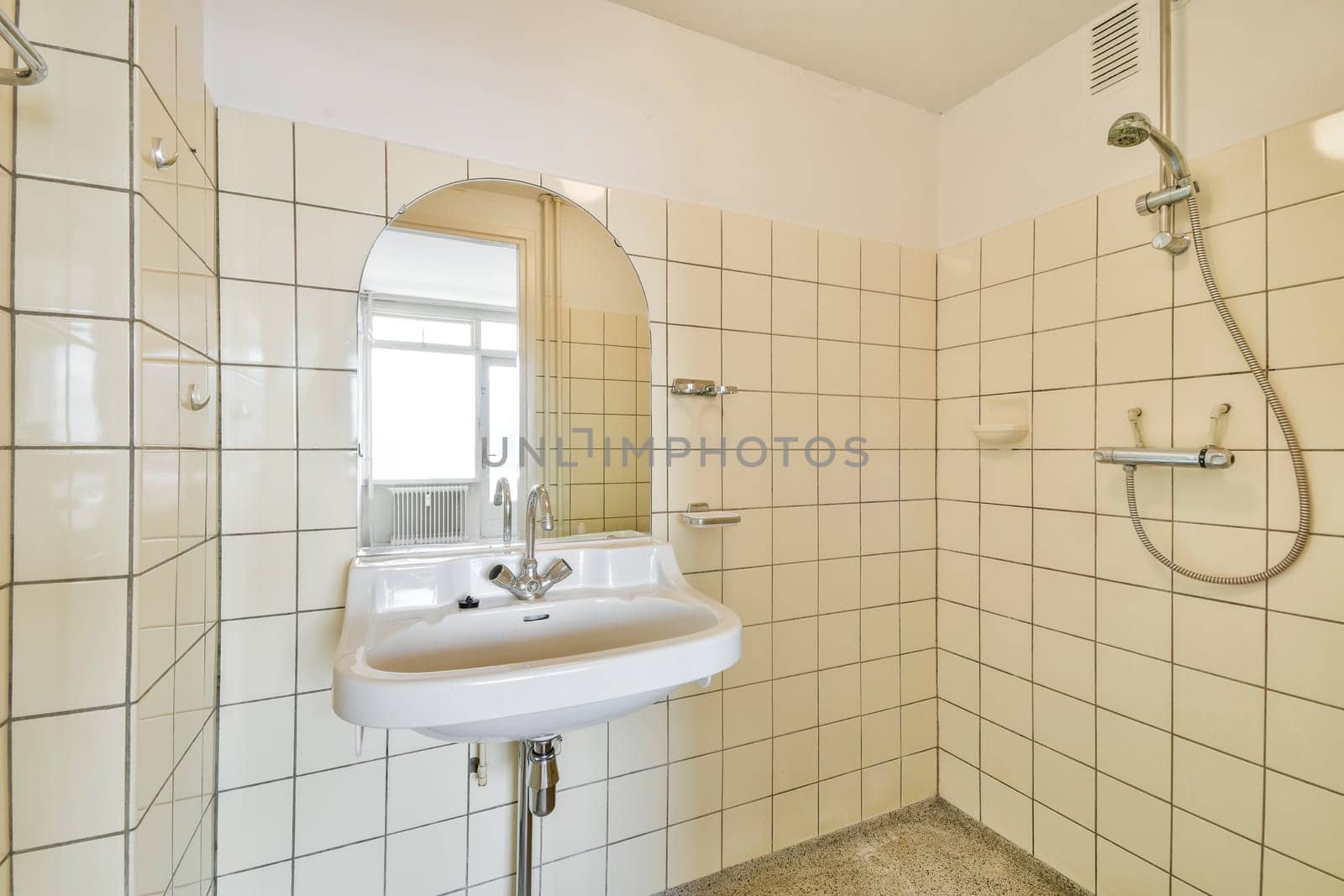 A sleek and minimalist bathroom featuring white tiles, a simple sink with a modern faucet, and an oval mirror. The space conveys a clean and refreshing ambiance.