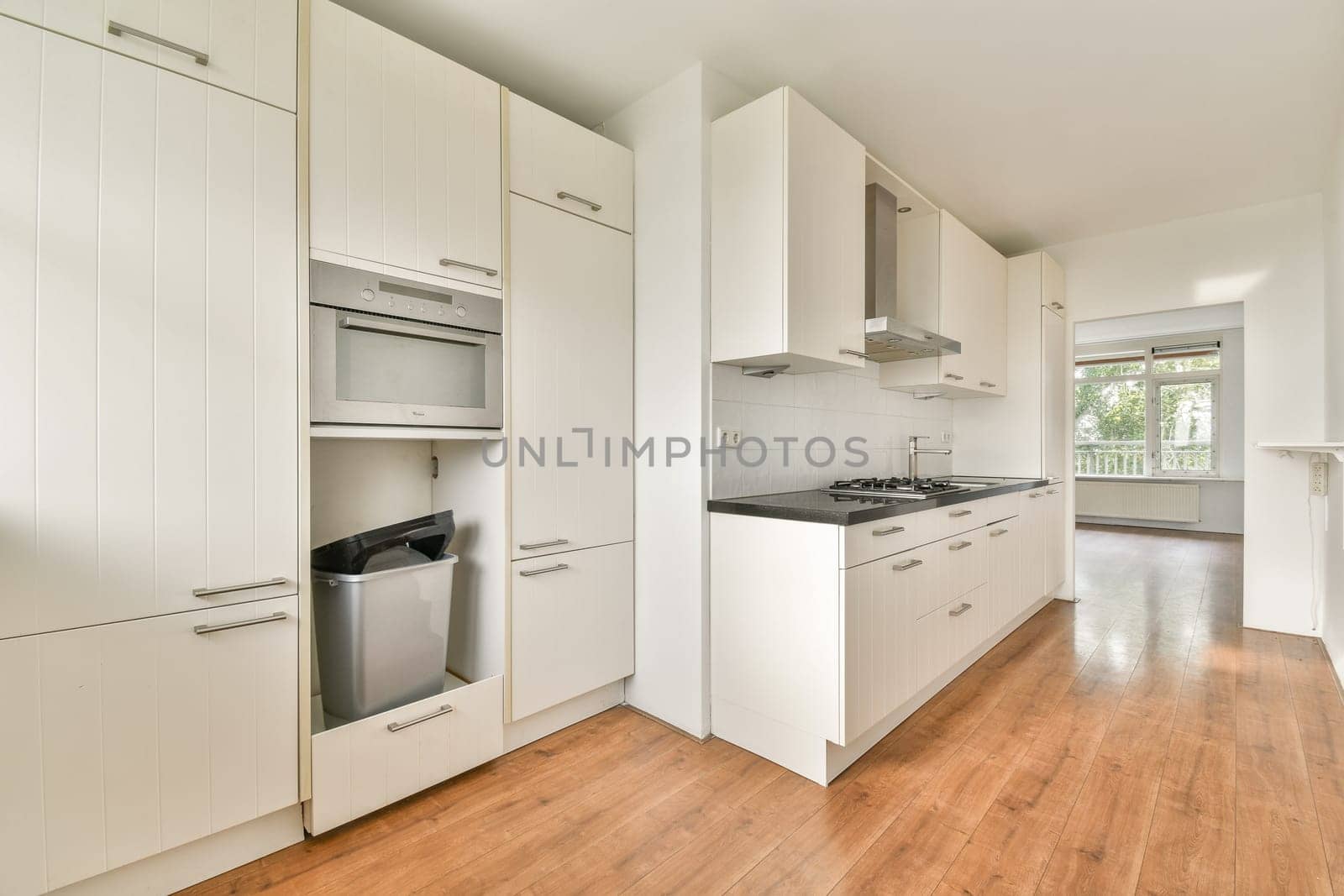 A sleek, modern kitchen showcasing minimalist design with white cabinets, stainless steel appliances, and a spacious layout for cooking and dining.