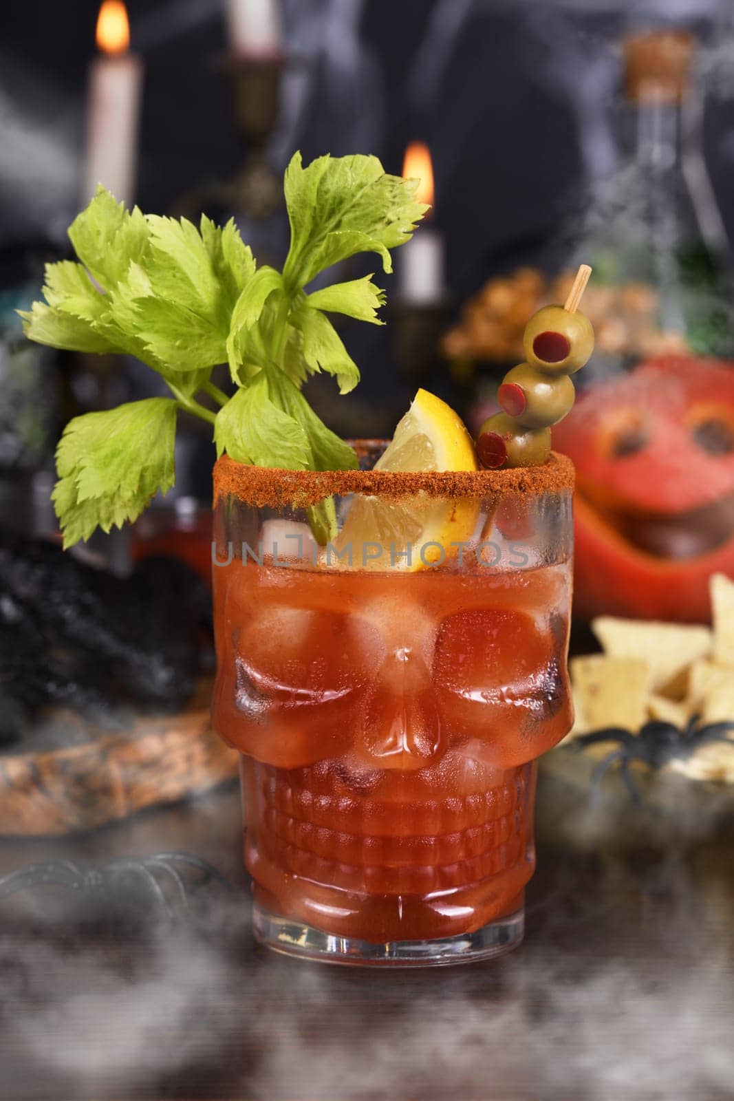 Michelada Cocktail, Bloody Mary. Mexican drink with tomato juice, lime juice, sauce and beer, garnished with celery stalk, lemon, olives. Halloween party ideas. 