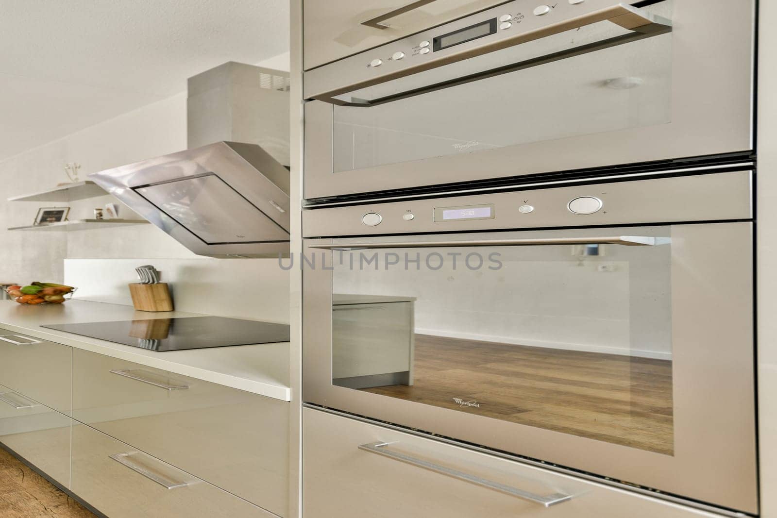 Sleek design of a contemporary kitchen featuring built-in appliances, minimalist cabinetry, and an elegant wooden floor. Emphasis on functionality and style.