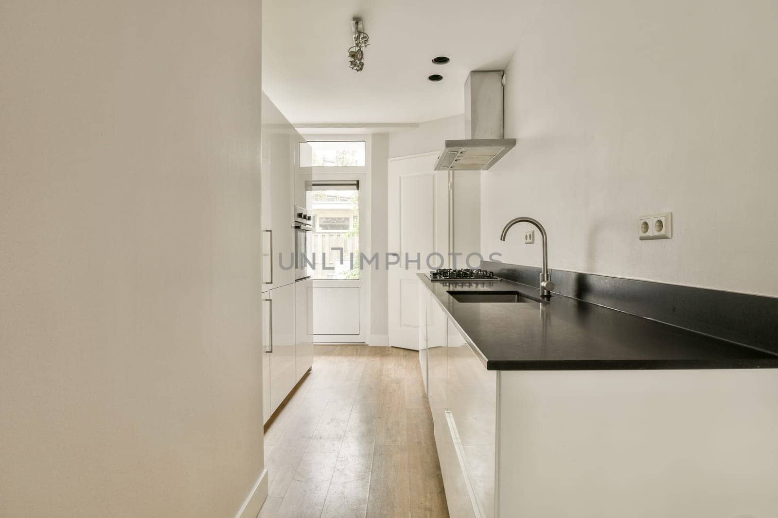 A sleek and modern kitchen showcasing a minimalist design with white cabinetry, a dark countertop, and ample natural light. Perfect for contemporary living.