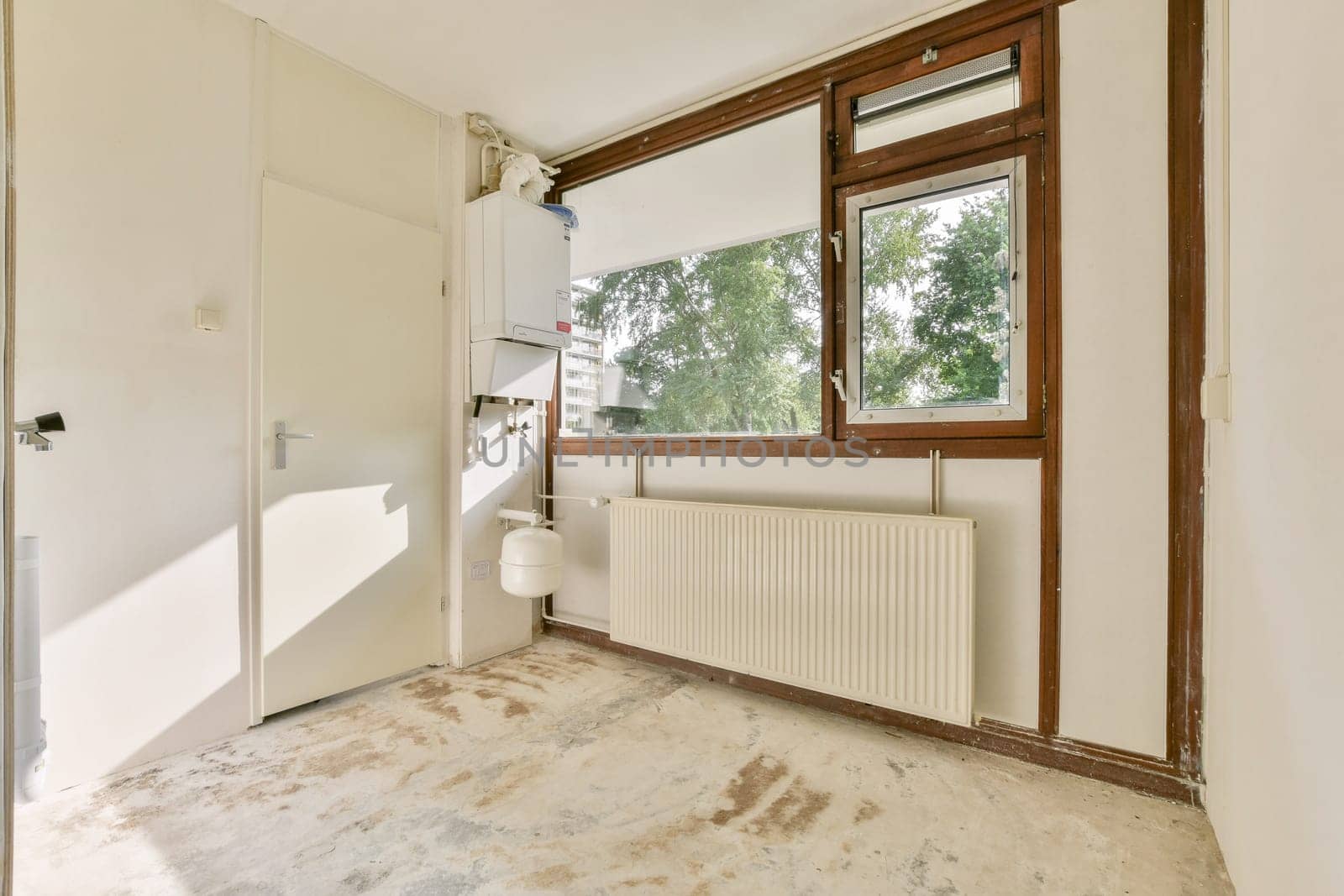 A spacious, modern room featuring large windows, neutral walls, and a minimalist design, allowing ample natural light to create an inviting atmosphere.