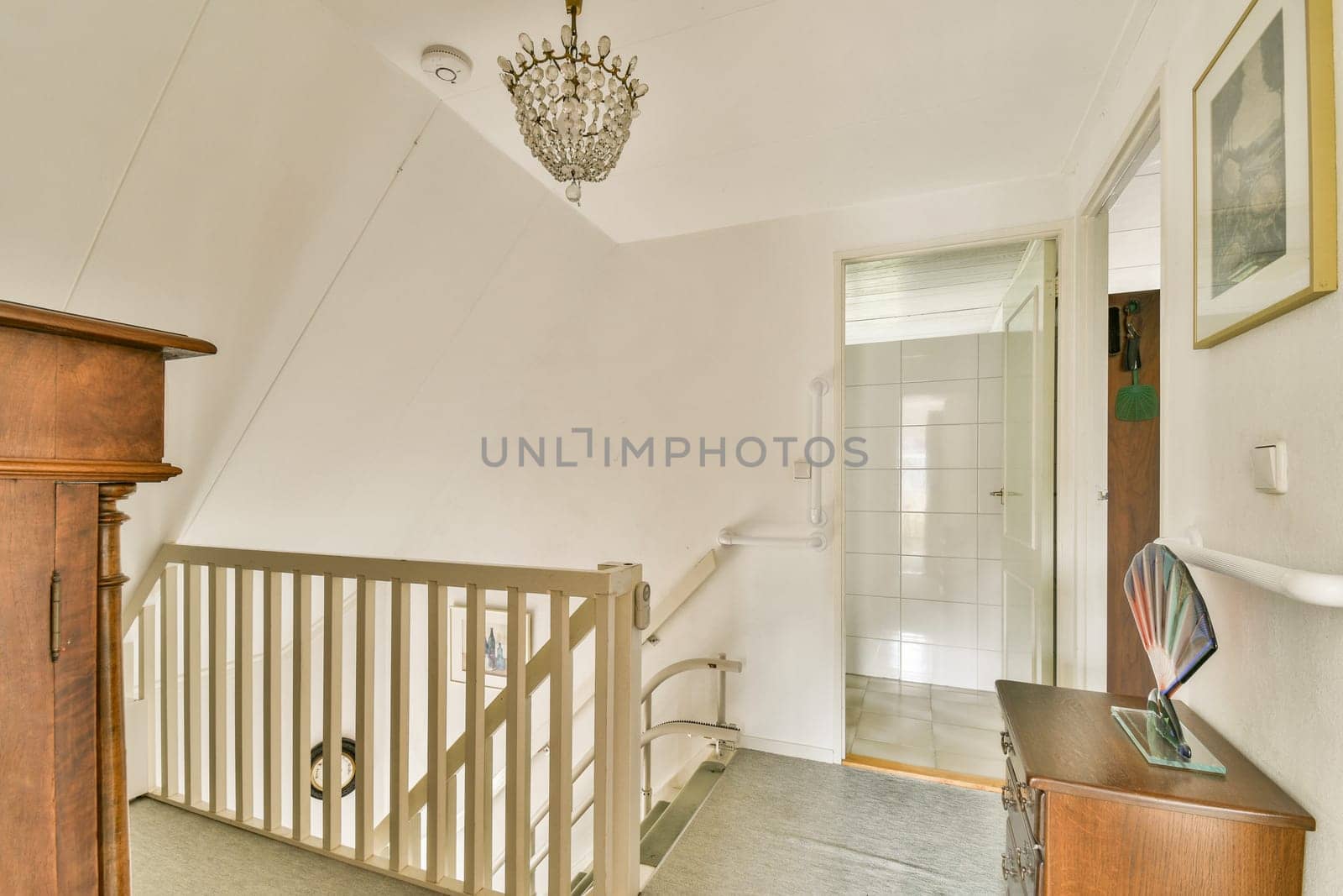 A beautifully designed staircase leading to a welcoming space, highlighted by a sparkling chandelier and minimalist decor.