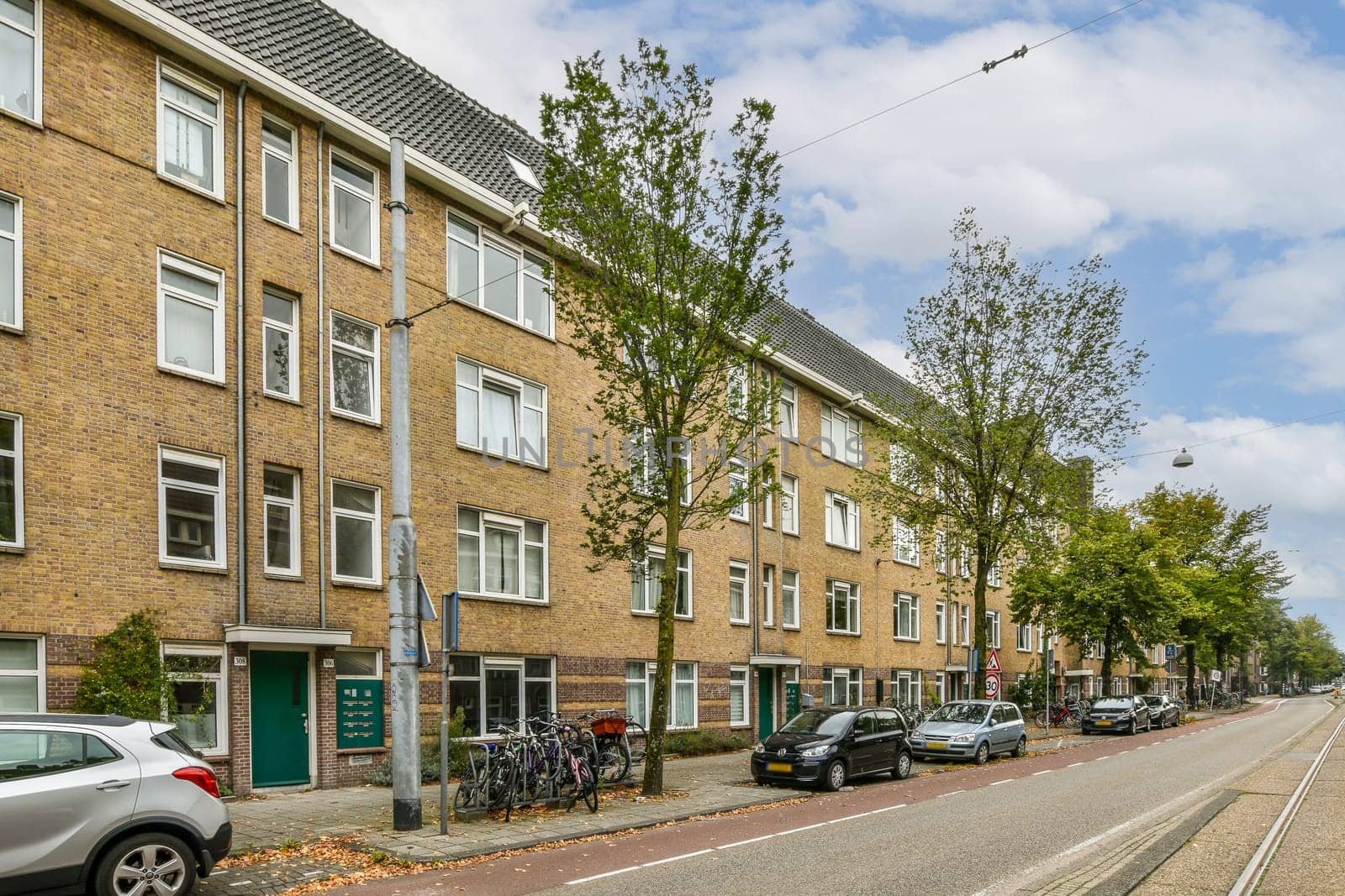 A picturesque urban street lined with residential buildings and trees, showcasing a quiet neighborhood atmosphere. Ideal for city living and community life.